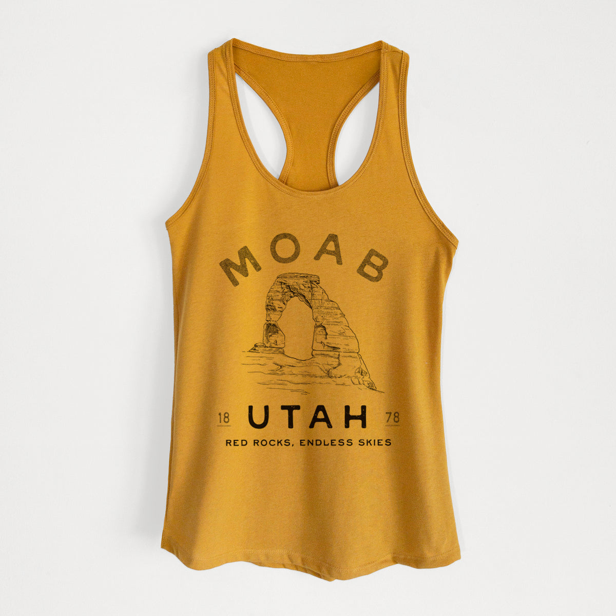 Gold women's racerback tank top laid flat, printed with a black ink illustration of Delicate Arch with the words Moab Utah, 1878.