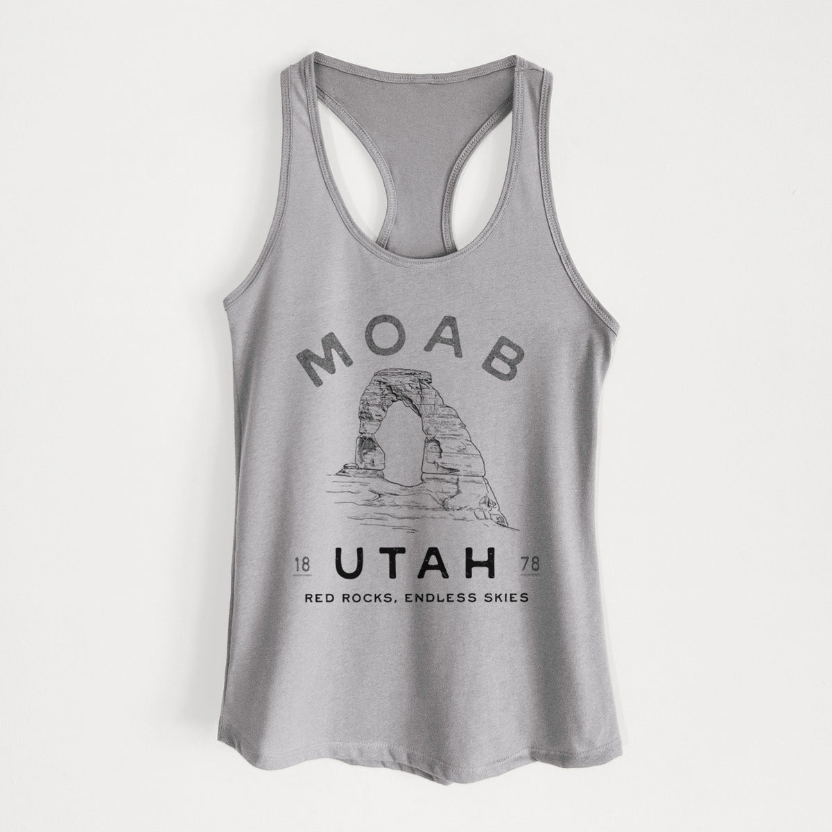 Heather grey women's racerback tank top laid flat, printed with a black ink illustration of Delicate Arch with the words Moab Utah, 1878.