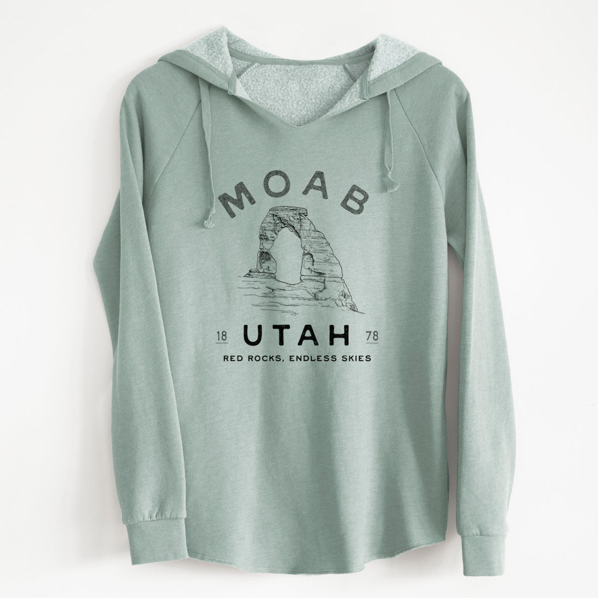Sage green women's Cali Wave hooded sweatshirt laid flat, printed with a black ink illustration of Delicate Arch with the words Moab Utah, 1878.
