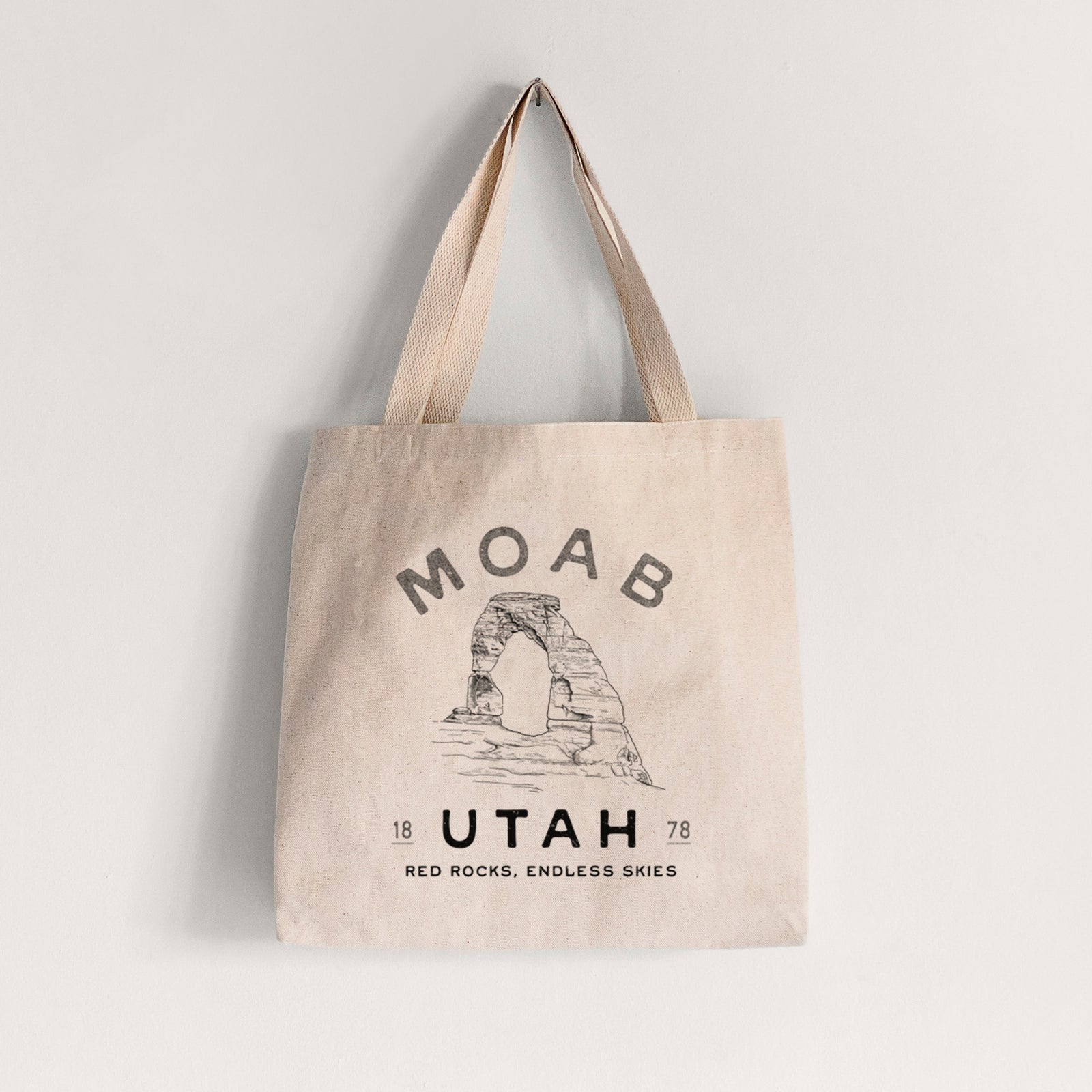 Natural canvas tote bag printed with a black ink illustration of Delicate Arch with the words Moab Utah, 1878.