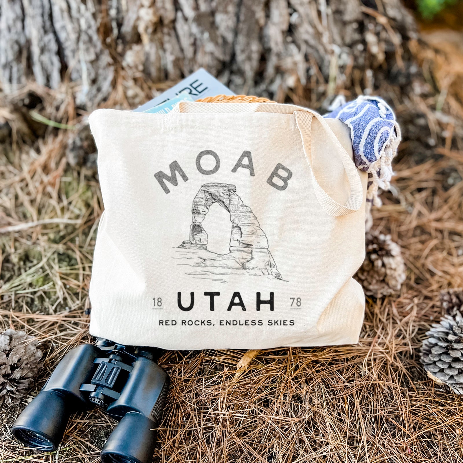 Natural canvas tote bag printed with a black ink illustration of Delicate Arch with the words Moab Utah, 1878.