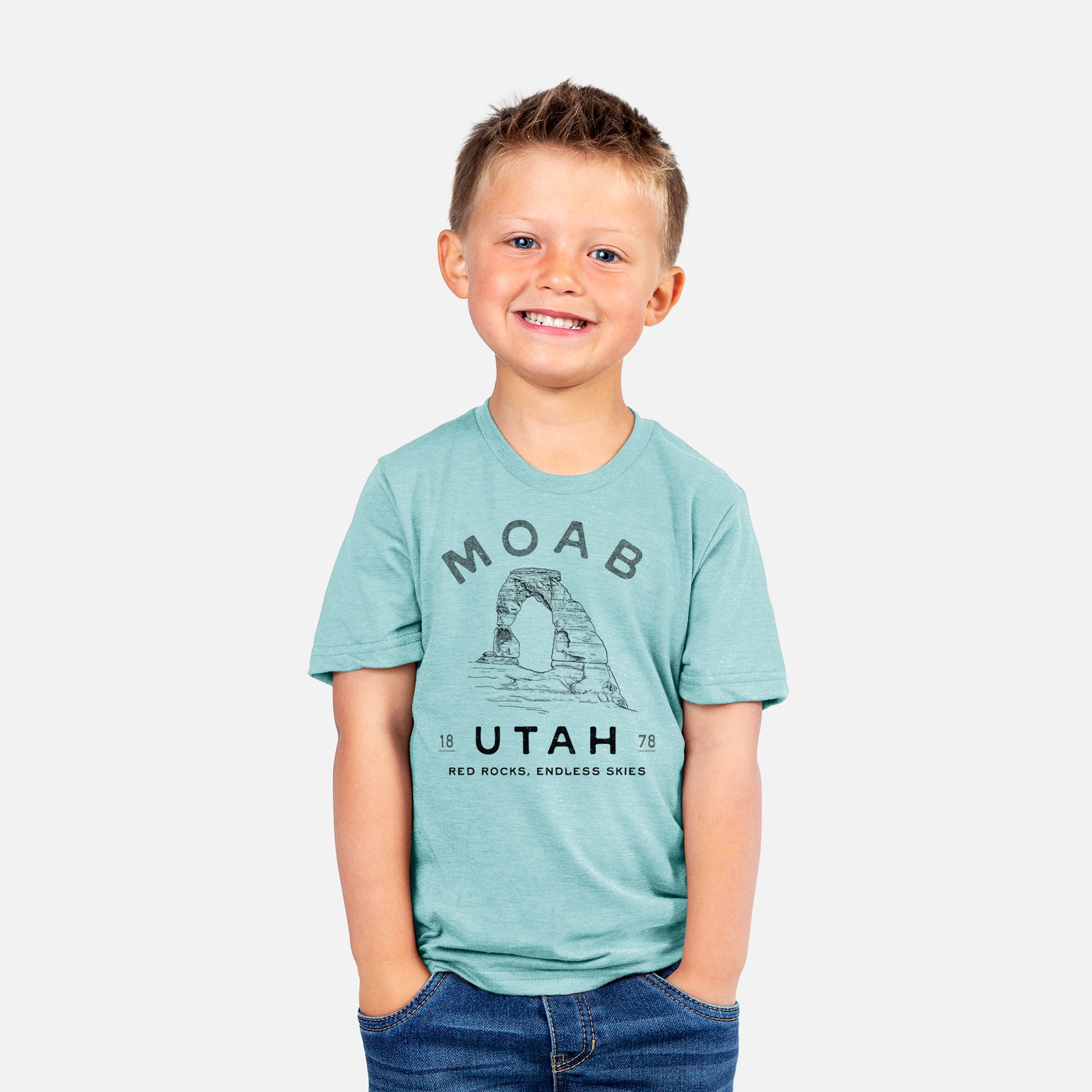 Two youth t-shirts in different colors on hangers, printed with a black ink illustration of Delicate Arch with the words Moab Utah, 1878.