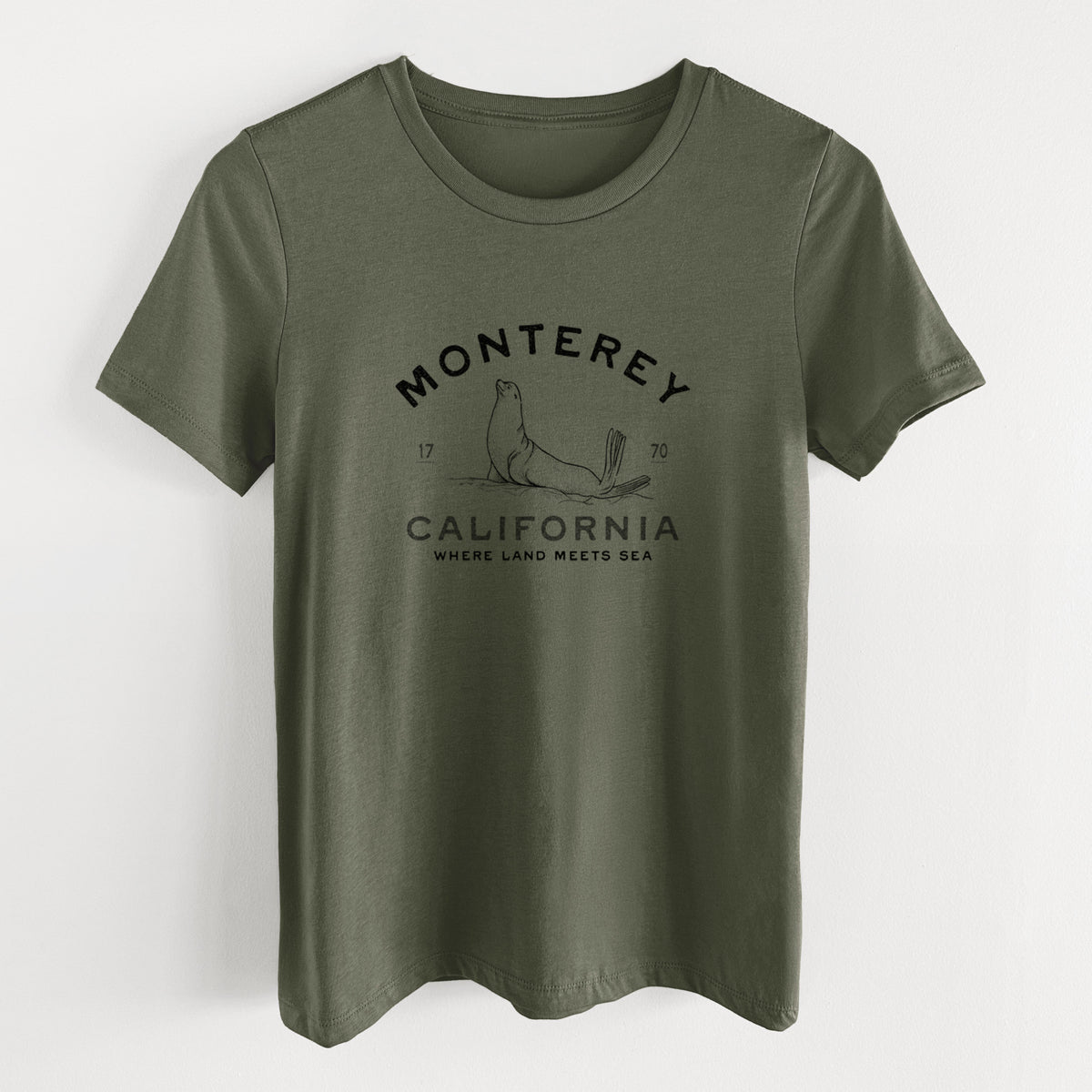 Military green women's relaxed fit cotton t-shirt laid flat, printed with a black ink sea lion with the words Monterey California, 1770, Where Land Meets Sea.