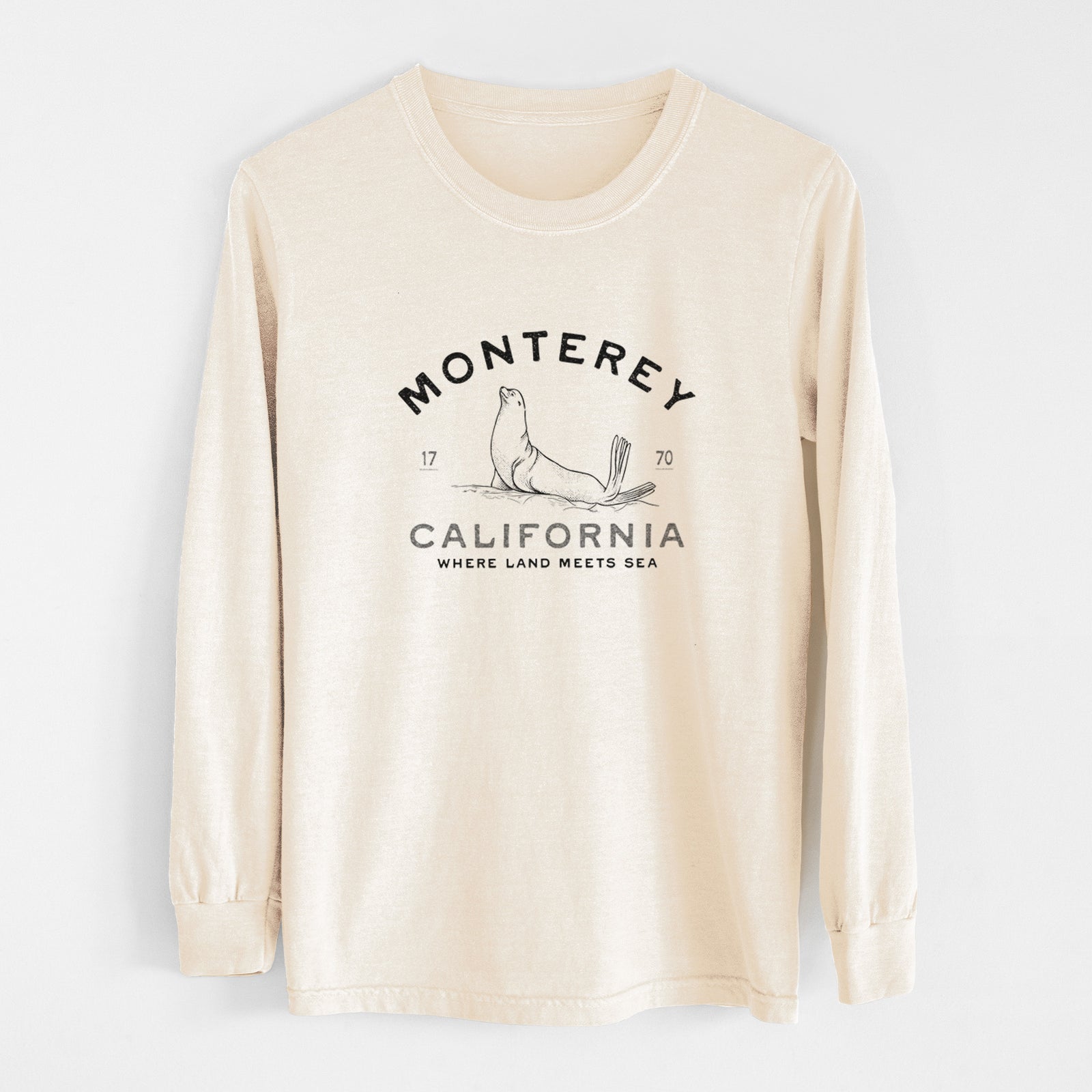 Ivory Comfort Colors long sleeve shirt laid flat, printed with a black ink sea lion with the words Monterey California, 1770, Where Land Meets Sea.