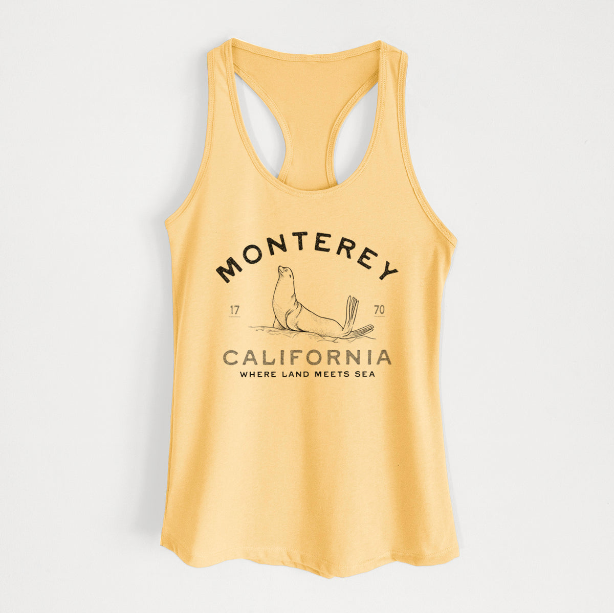 Banana cream women's racerback tank top laid flat, printed with a black ink sea lion with the words Monterey California, 1770, Where Land Meets Sea.