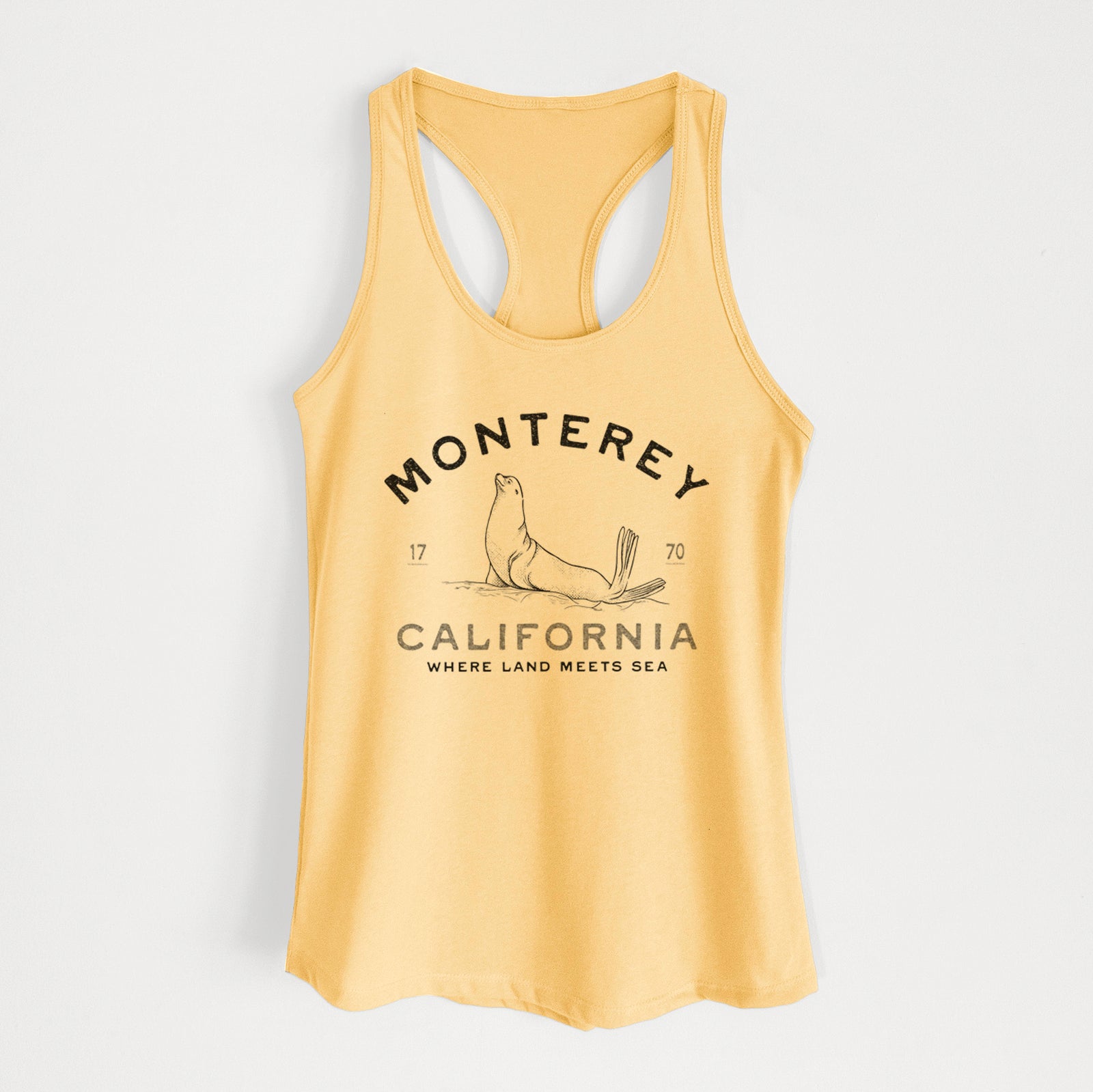 Banana cream women's racerback tank top laid flat, printed with a black ink sea lion with the words Monterey California, 1770, Where Land Meets Sea.