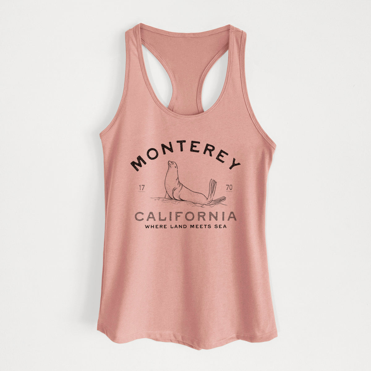 Desert pink women's racerback tank top laid flat, printed with a black ink sea lion with the words Monterey California, 1770, Where Land Meets Sea.