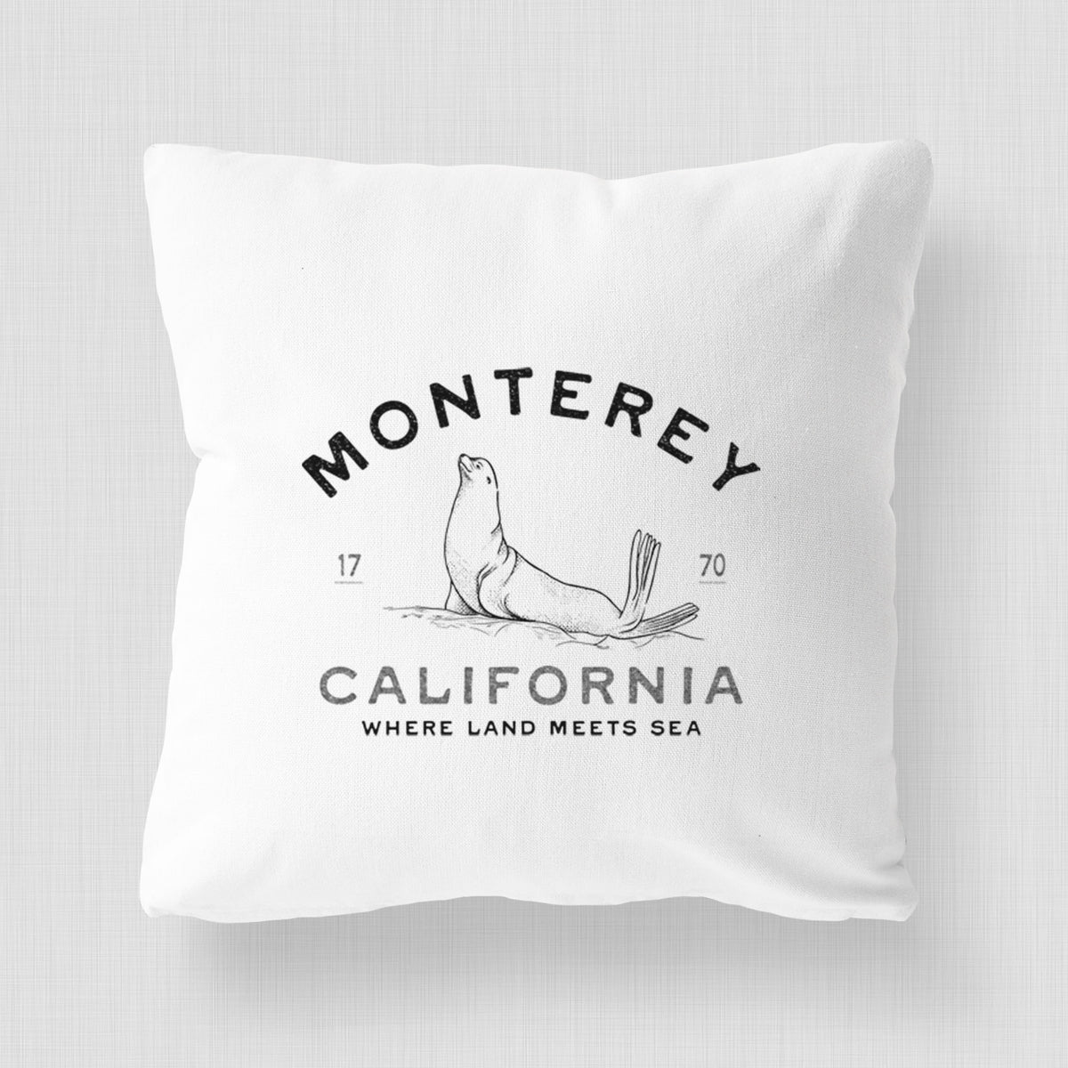 White pillow cover printed with a black ink sea lion with the words Monterey California, 1770, Where Land Meets Sea.