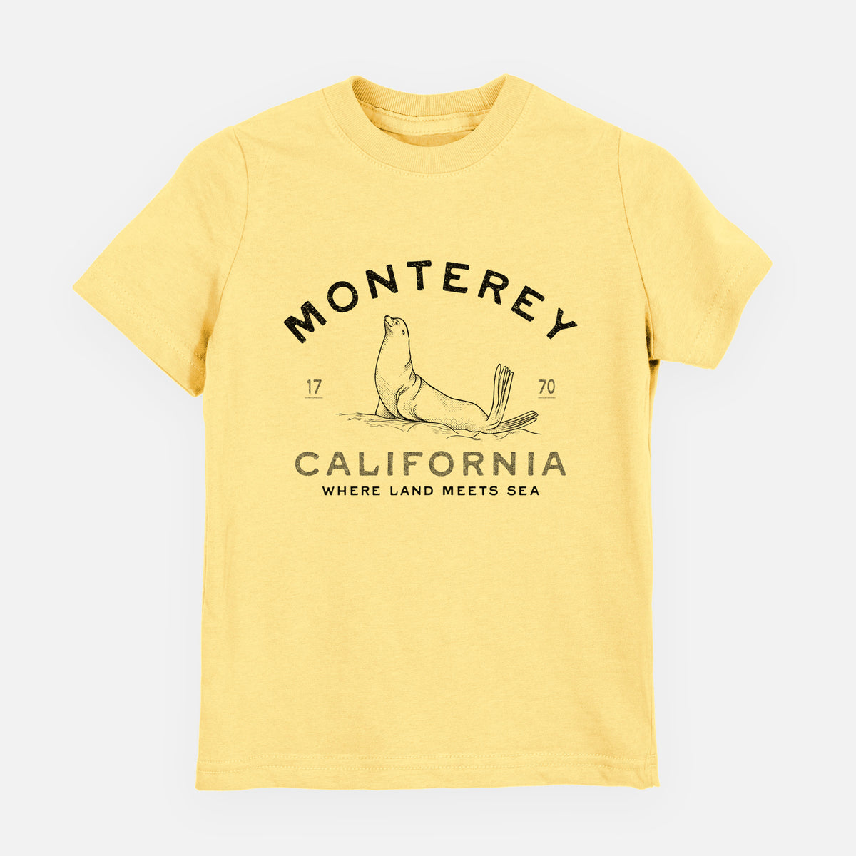 Butter yellow youth t-shirt laid flat, printed with a black ink sea lion with the words Monterey California, 1770, Where Land Meets Sea.