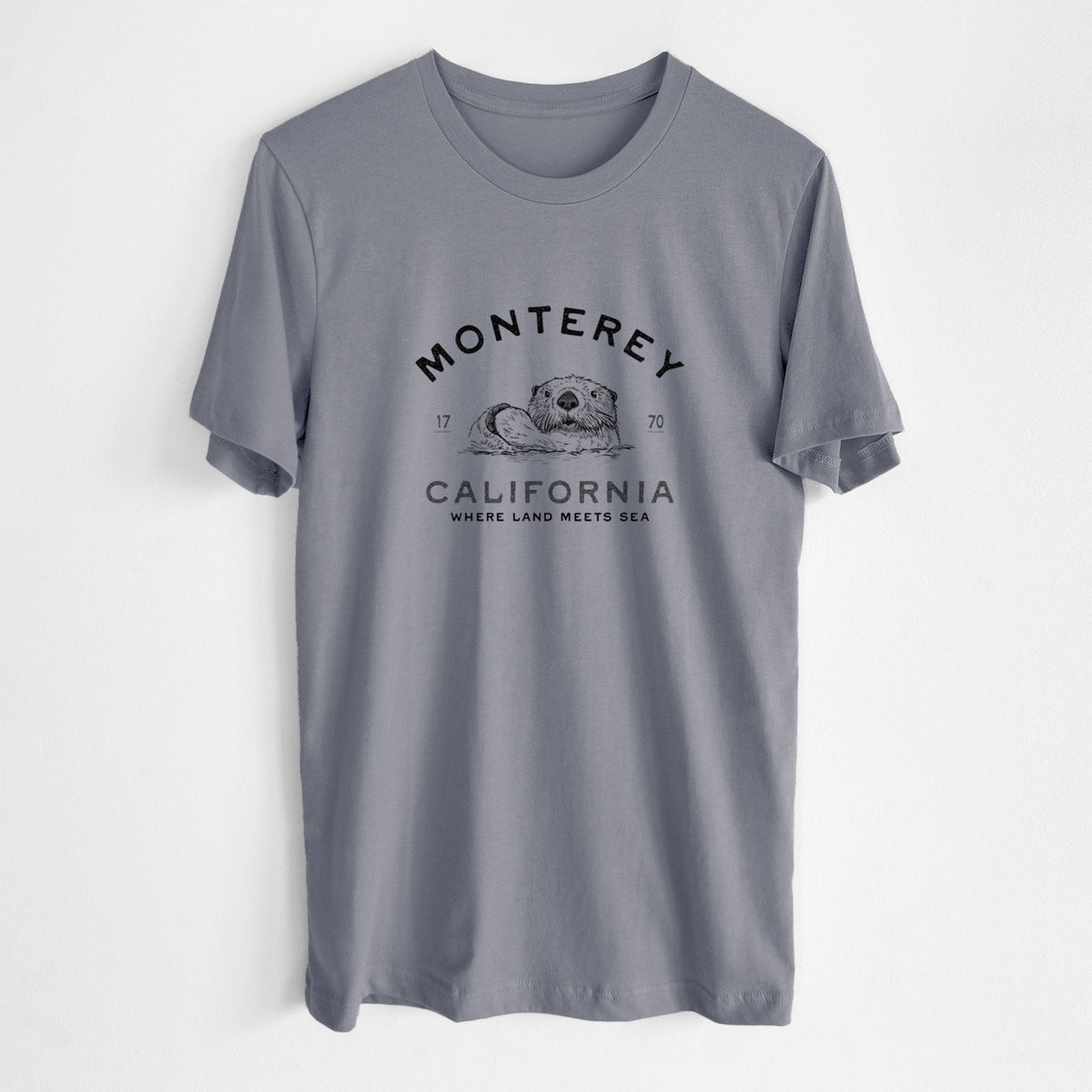Storm grey lightweight cotton t-shirt laid flat, printed with a black ink sea otter floating on its back, with the words Monterey California, 1770, Where Land Meets Sea.