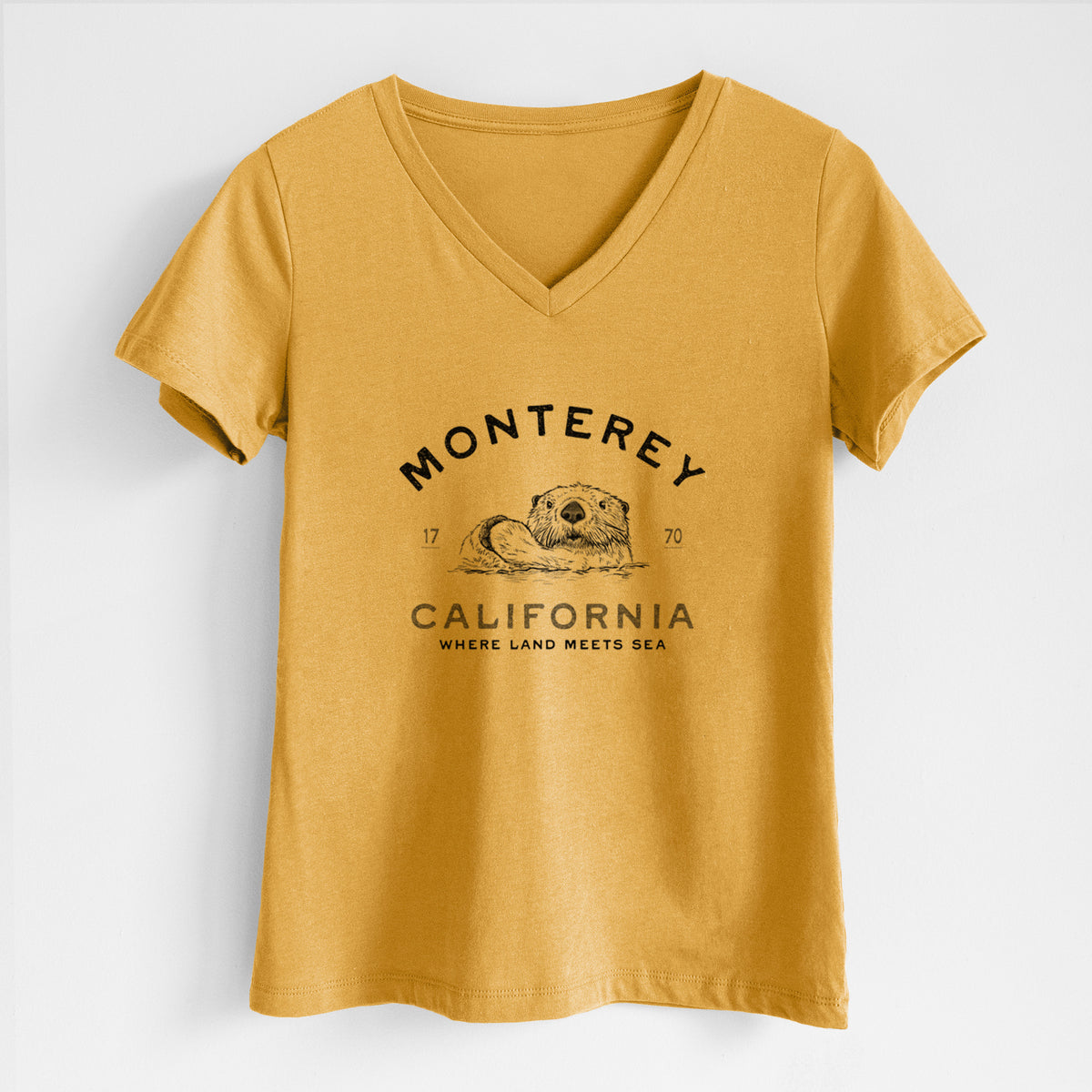 Honeycomb yellow women's relaxed fit cotton V-neck t-shirt laid flat, printed with a black ink sea otter floating on its back, with the words Monterey California, 1770, Where Land Meets Sea.