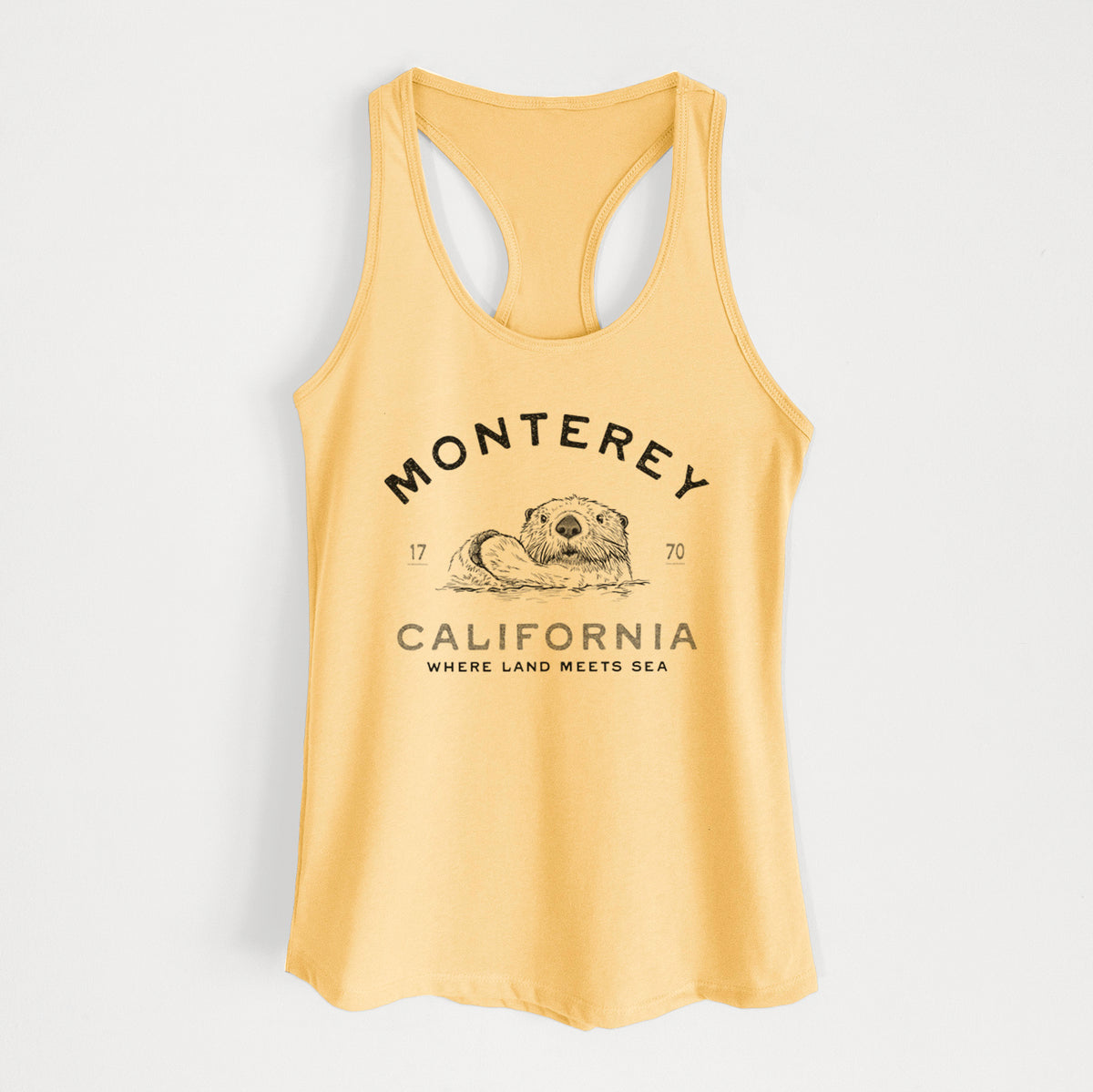 Banana cream women's racerback tank top laid flat, printed with a black ink sea otter floating on its back, with the words Monterey California, 1770, Where Land Meets Sea.