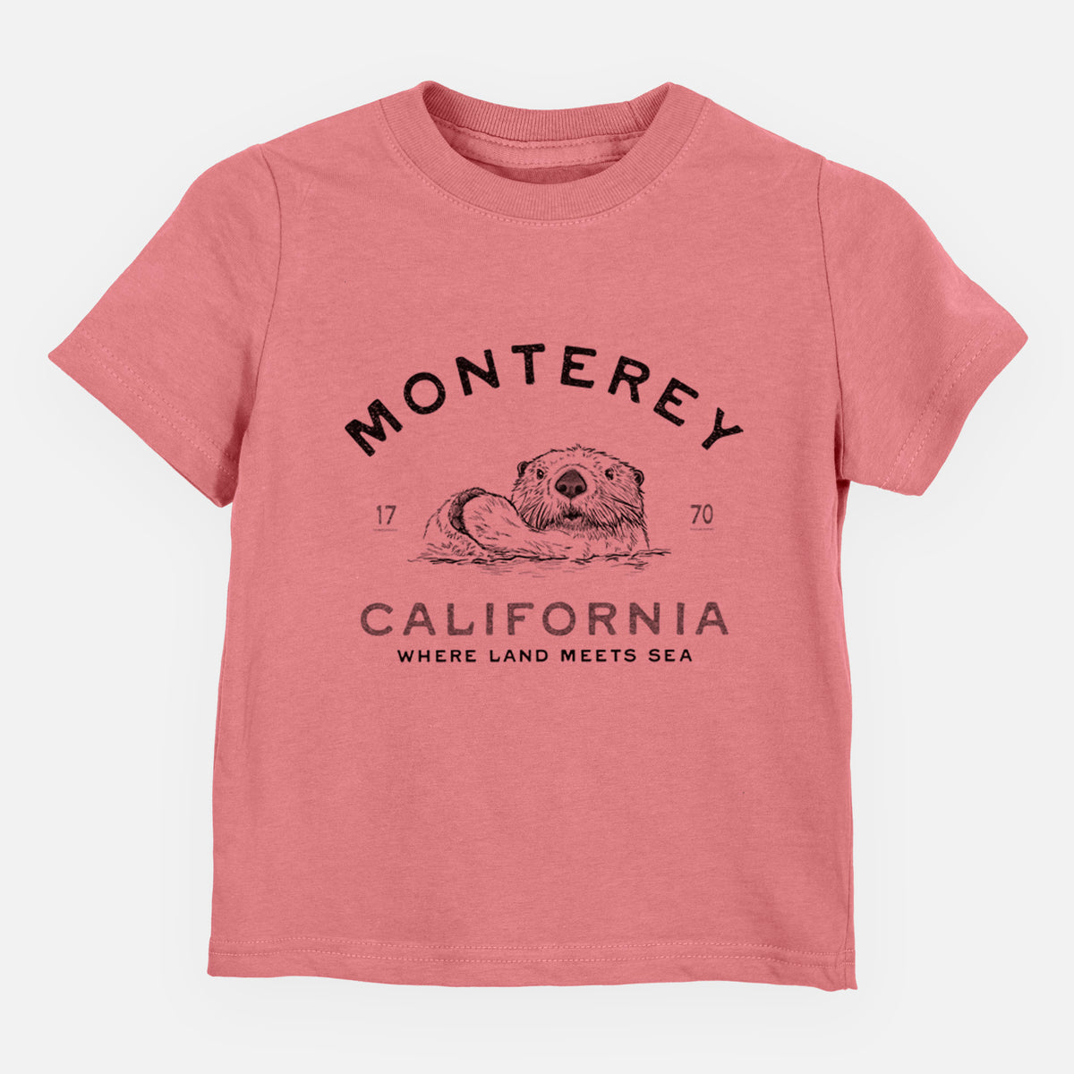 Mauve pink toddler t-shirt laid flat, printed with a black ink sea otter floating on its back, with the words Monterey California, 1770, Where Land Meets Sea.