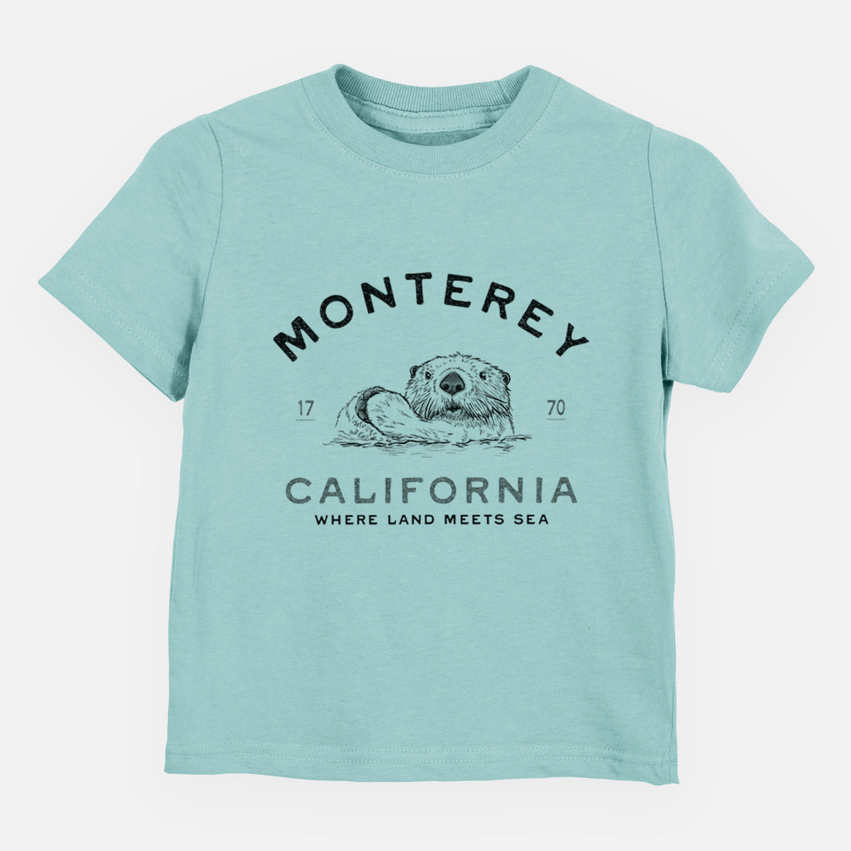 Saltwater toddler t-shirt laid flat, printed with a black ink sea otter floating on its back, with the words Monterey California, 1770, Where Land Meets Sea.