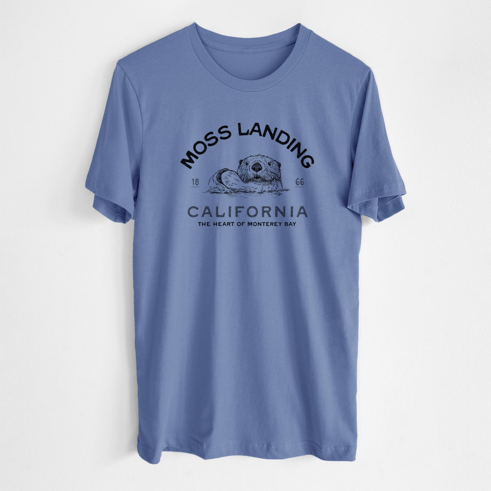 Blue bell lightweight cotton t-shirt laid flat, printed with a black ink sea otter with the words Moss Landing California, 1866, The Heart of Monterey Bay.