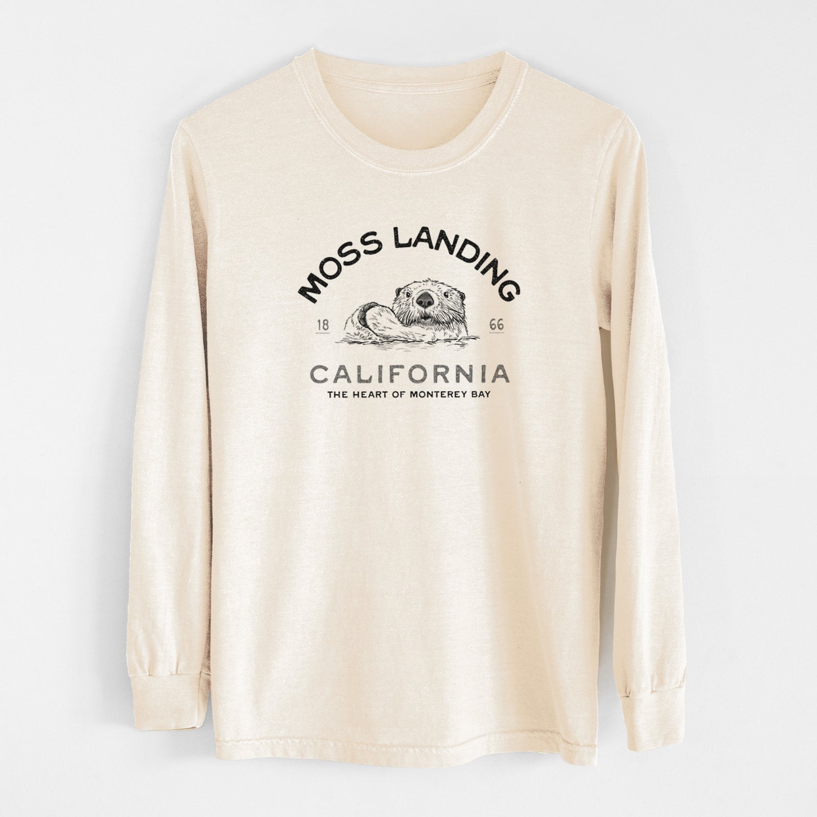 Ivory Comfort Colors long sleeve shirt laid flat, printed with a black ink sea otter with the words Moss Landing California, 1866, The Heart of Monterey Bay.
