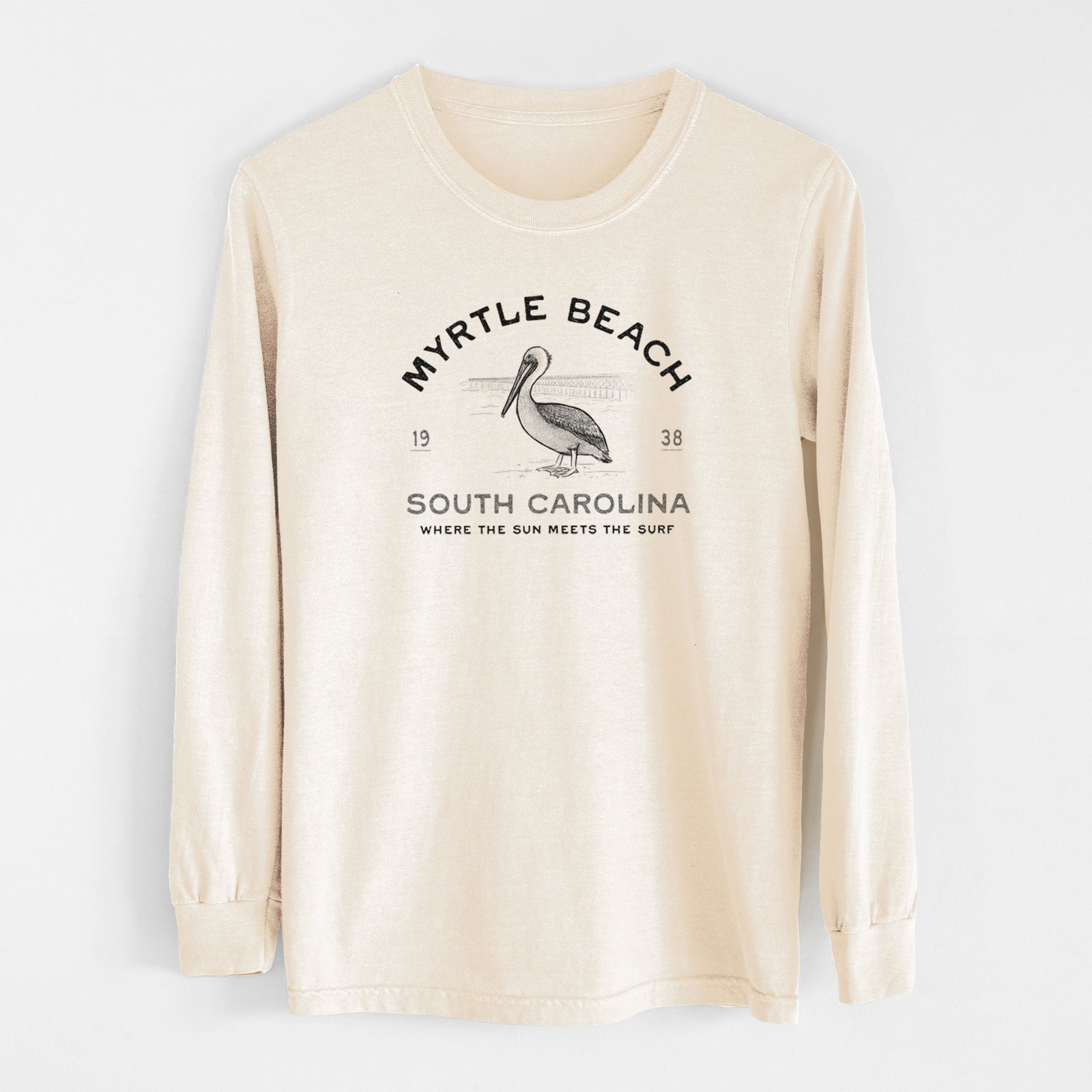 Ivory Comfort Colors long sleeve shirt laid flat, printed with a black ink pelican on a post with the words Myrtle Beach South Carolina, Where the Sun Meets the Surf.
