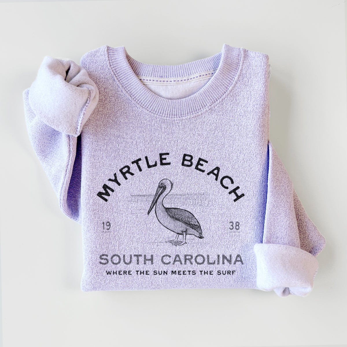 Ice purple knit sweatshirt printed with a black ink pelican on a post with the words Myrtle Beach South Carolina, Where the Sun Meets the Surf, styled flat.