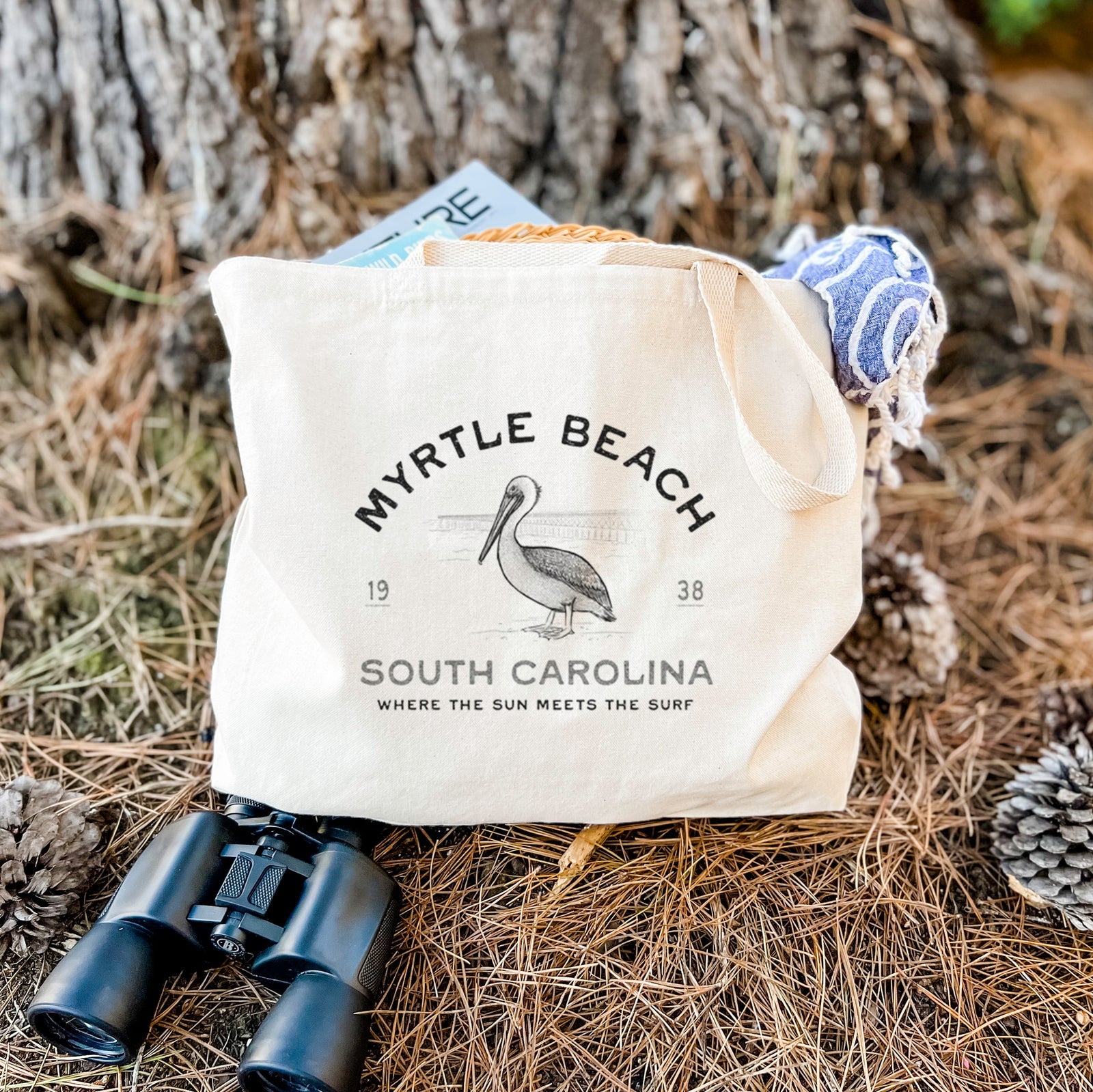 Natural canvas tote bag printed with a black ink pelican on a post with the words Myrtle Beach South Carolina, Where the Sun Meets the Surf.