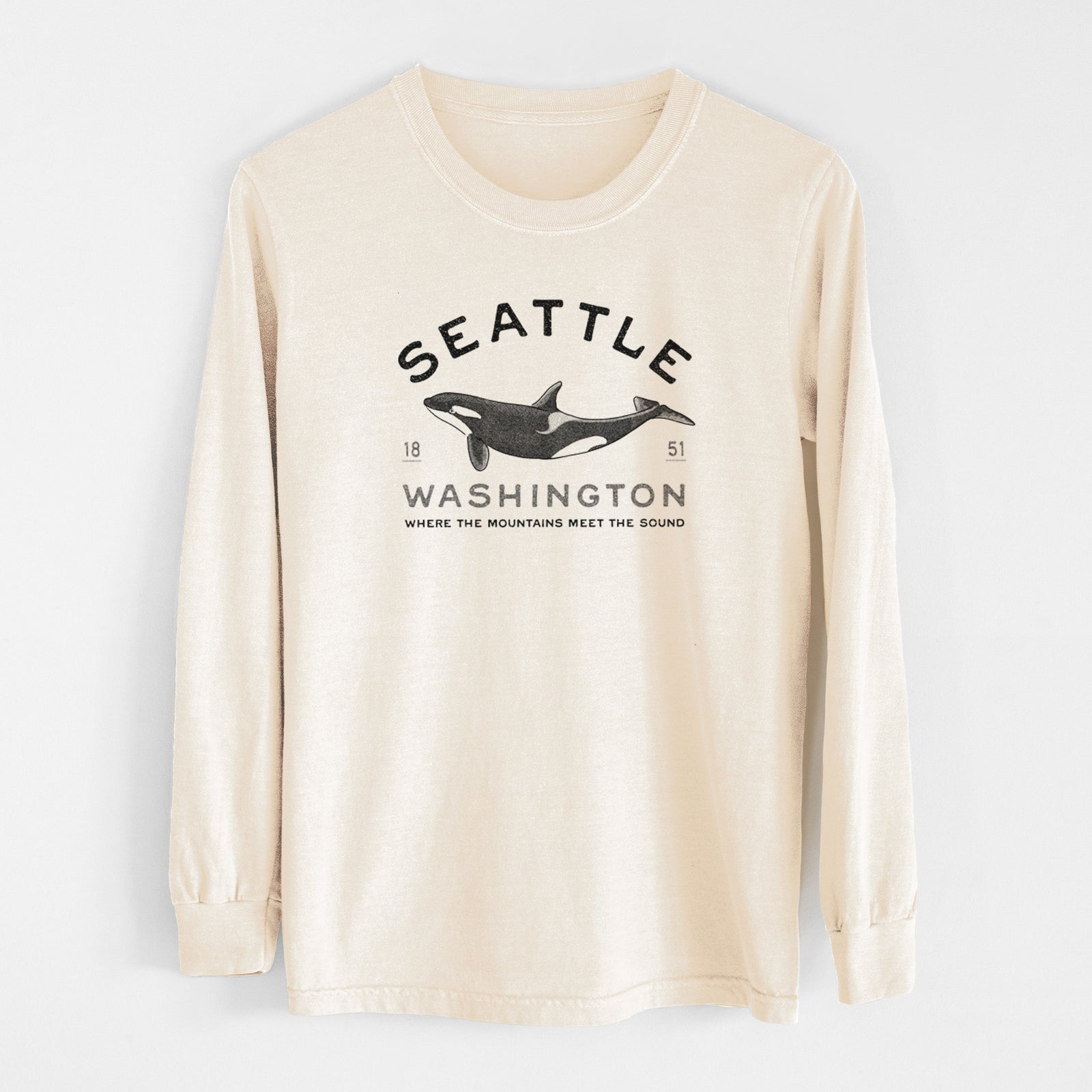 Ivory Comfort Colors long sleeve shirt laid flat, printed with a black ink orca with the words Seattle Washington, 1851, Where the Mountains Meet the Sound.