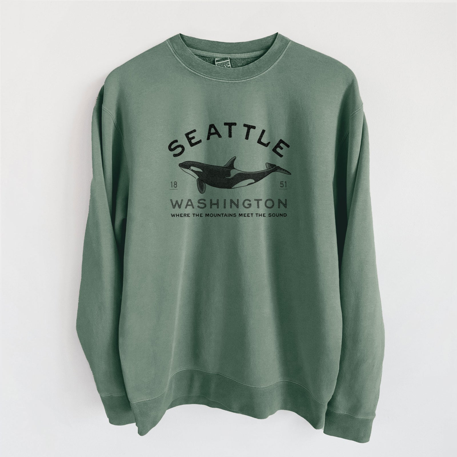 Alpine green pigment dyed crewneck sweatshirt laid flat, printed with a black ink orca with the words Seattle Washington, 1851, Where the Mountains Meet the Sound.