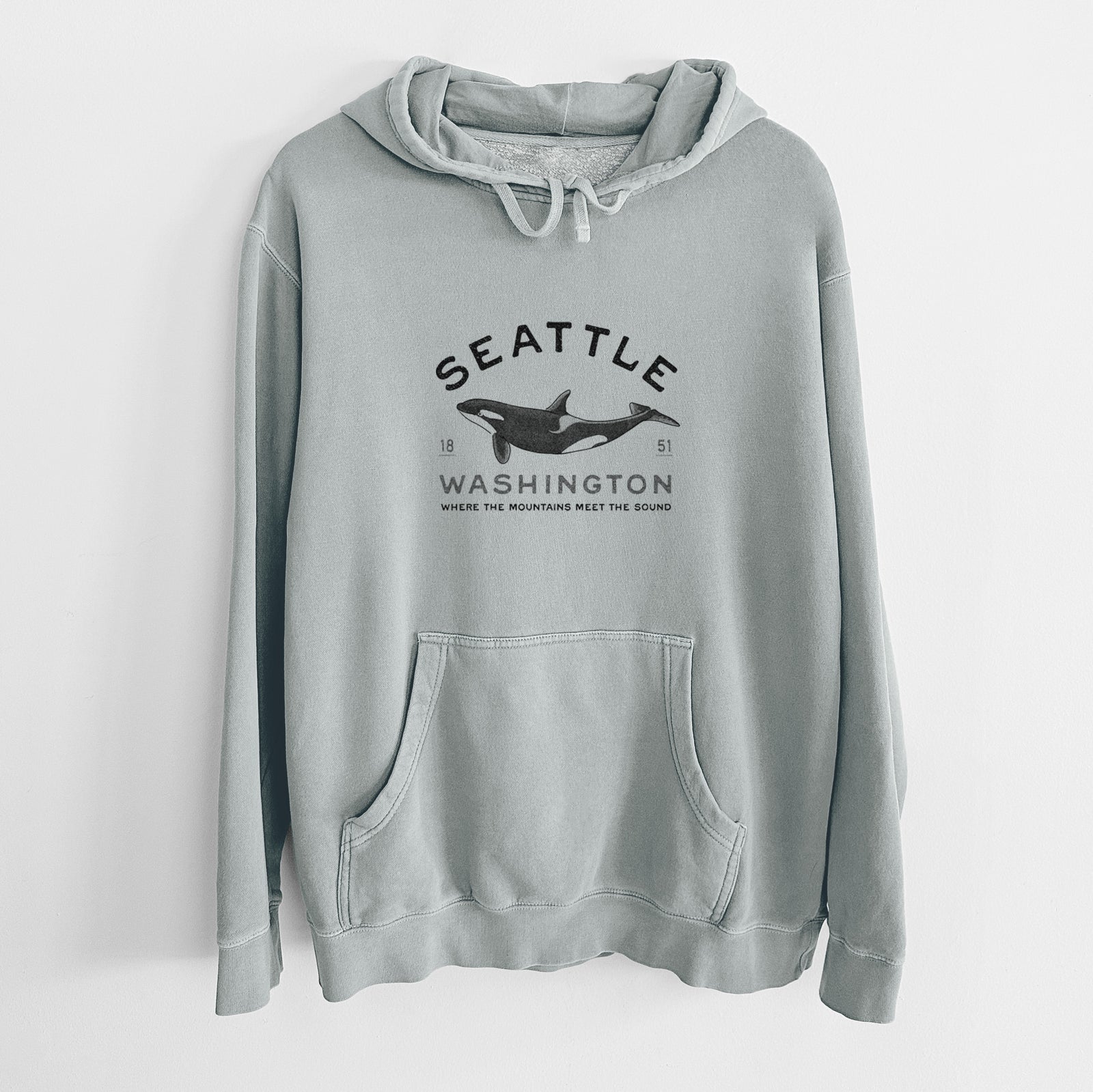 Sage green pigment dyed hoodie laid flat, printed with a black ink orca with the words Seattle Washington, 1851, Where the Mountains Meet the Sound.