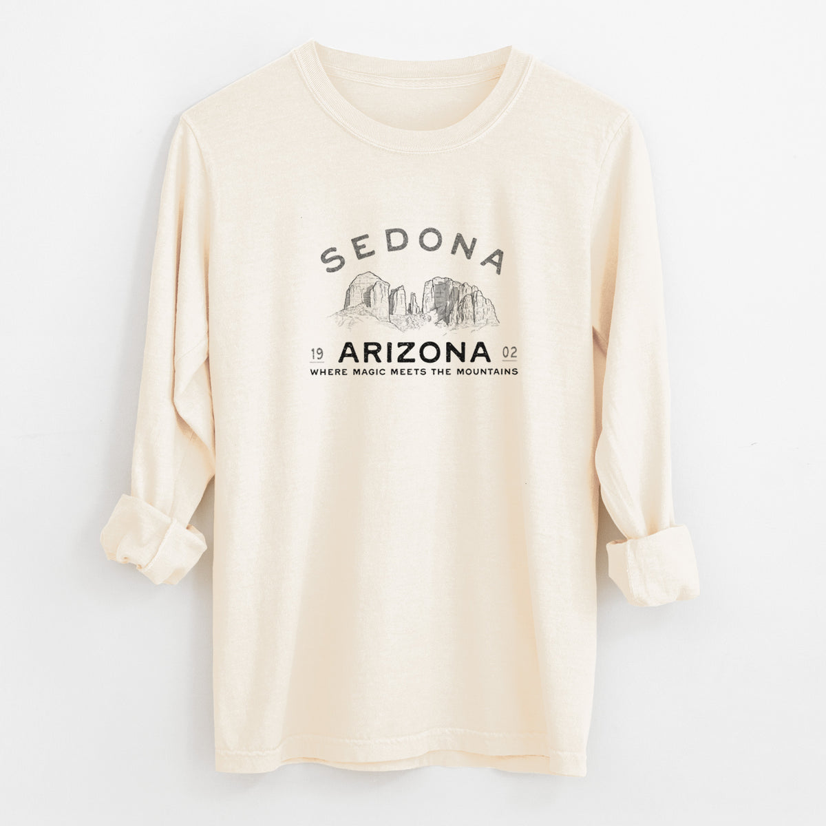 Ivory Comfort Colors long sleeve shirt laid flat with the cuffs rolled, printed with black ink red rock buttes with the words Sedona Arizona, Where Magic Meets the Mountains.