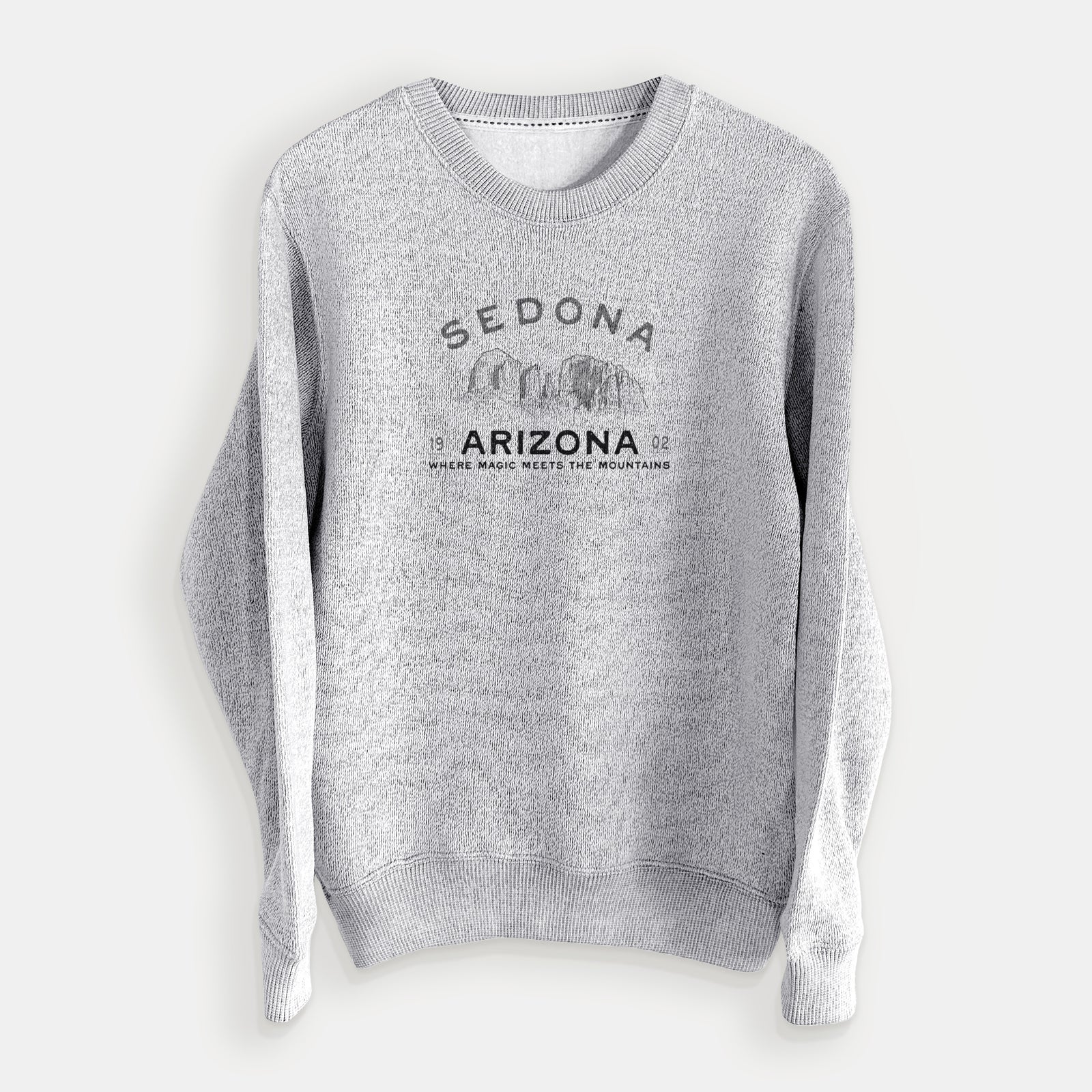Salt and pepper knit sweatshirt laid flat, printed with black ink red rock buttes with the words Sedona Arizona, Where Magic Meets the Mountains.