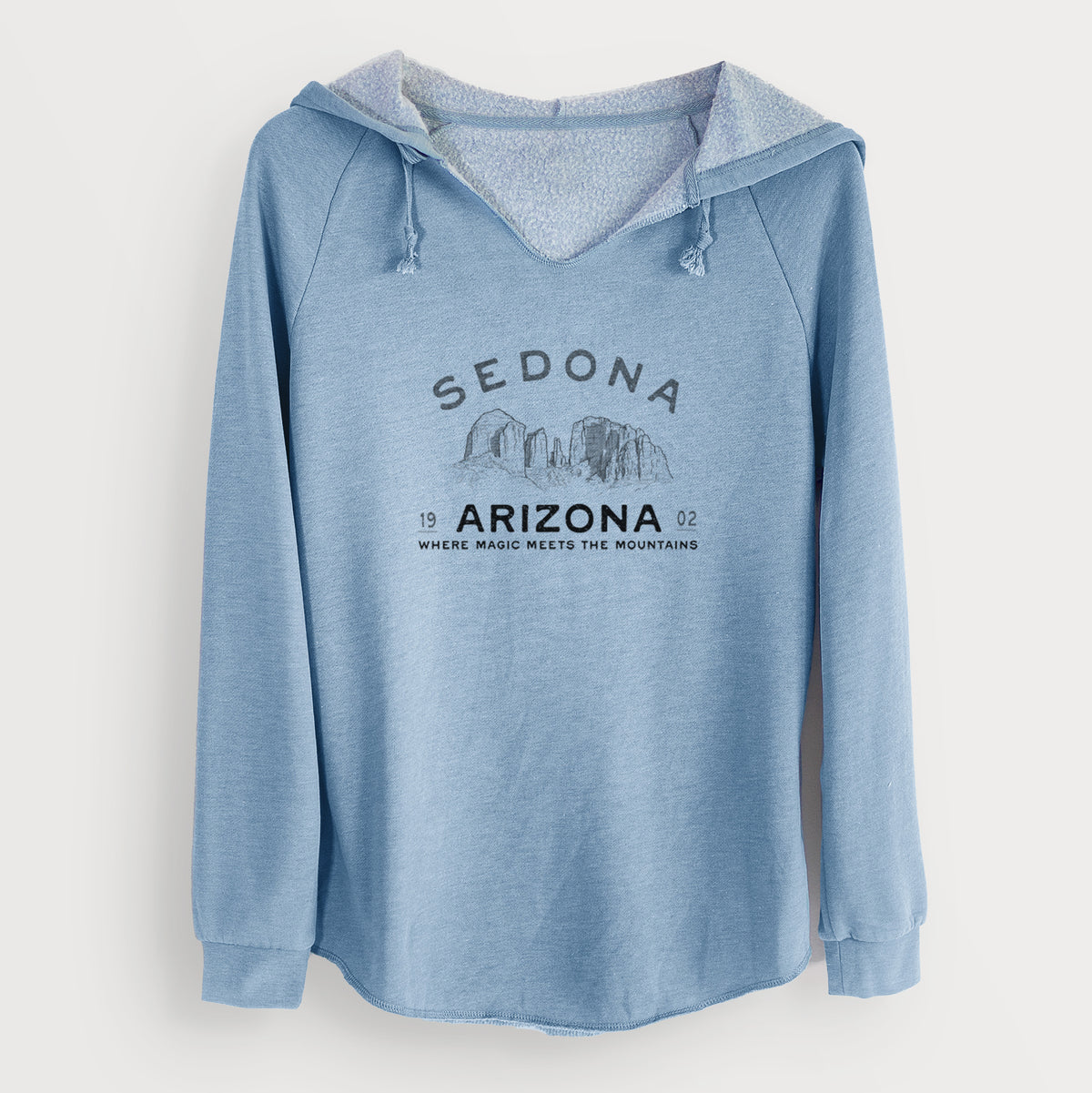 Misty blue women's Cali Wave hooded sweatshirt laid flat, printed with black ink red rock buttes with the words Sedona Arizona, Where Magic Meets the Mountains.