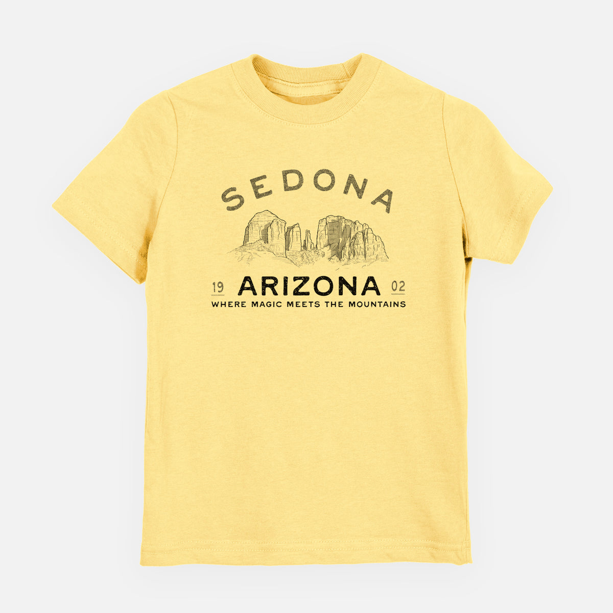 Butter yellow youth t-shirt laid flat, printed with black ink red rock buttes with the words Sedona Arizona, Where Magic Meets the Mountains.