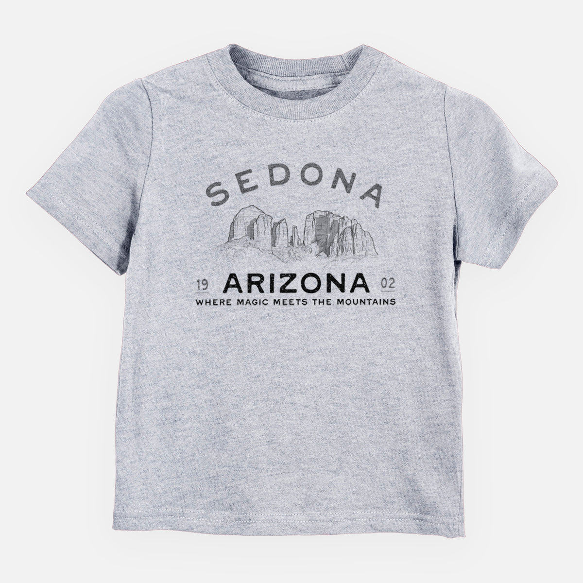 Heather grey toddler t-shirt laid flat, printed with black ink red rock buttes with the words Sedona Arizona, Where Magic Meets the Mountains.