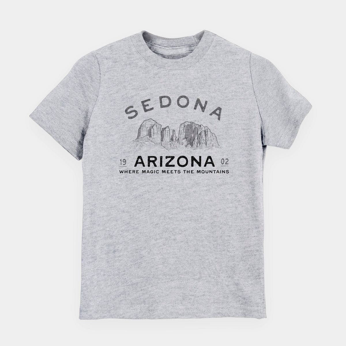 Heather grey youth t-shirt laid flat, printed with black ink red rock buttes with the words Sedona Arizona, Where Magic Meets the Mountains.