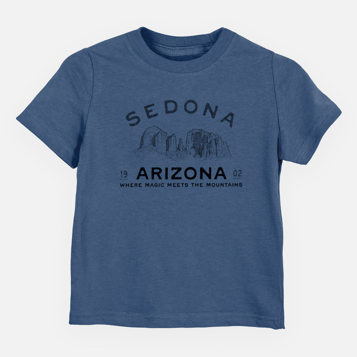 Indigo blue toddler t-shirt laid flat, printed with black ink red rock buttes with the words Sedona Arizona, Where Magic Meets the Mountains.