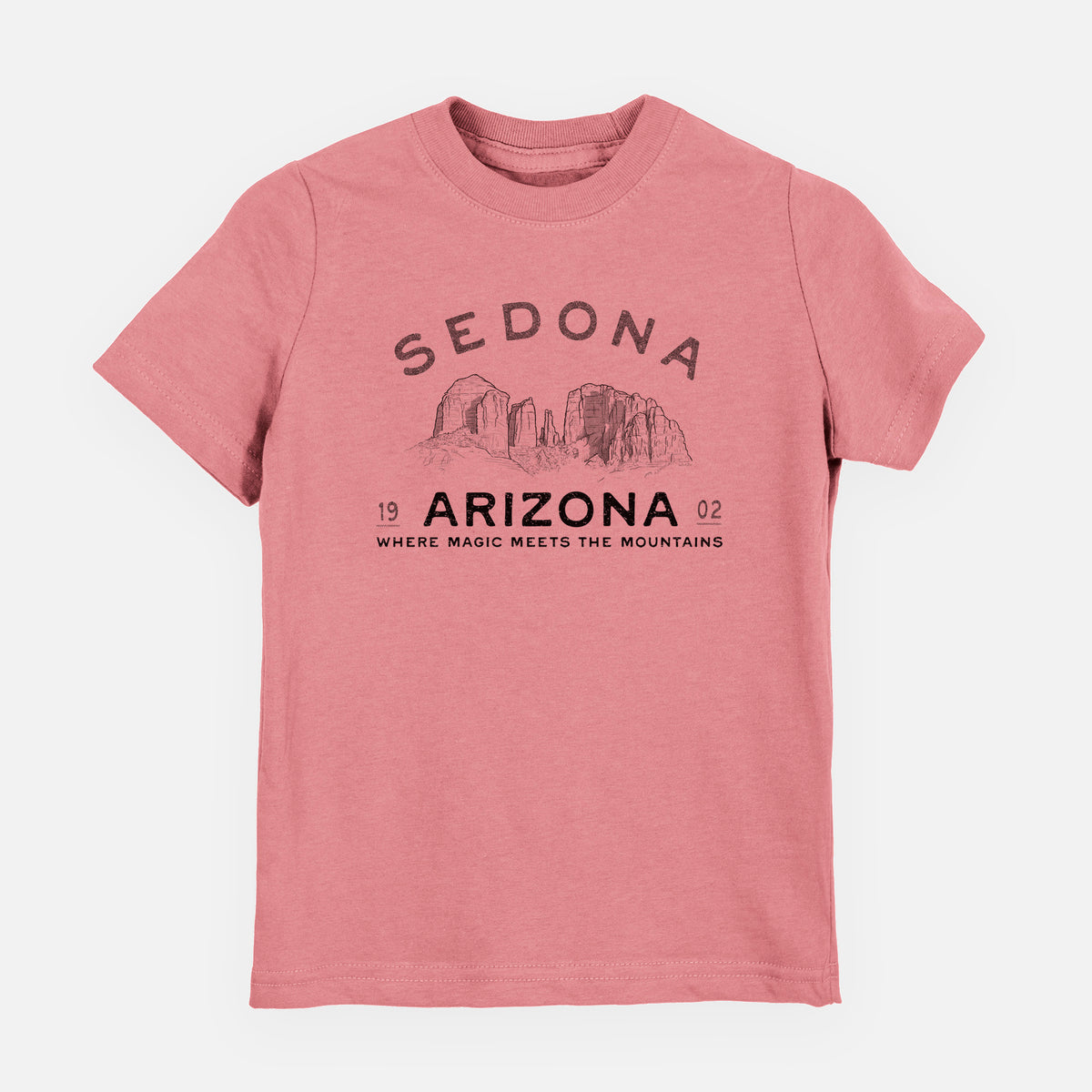 Mauve pink youth t-shirt laid flat, printed with black ink red rock buttes with the words Sedona Arizona, Where Magic Meets the Mountains.