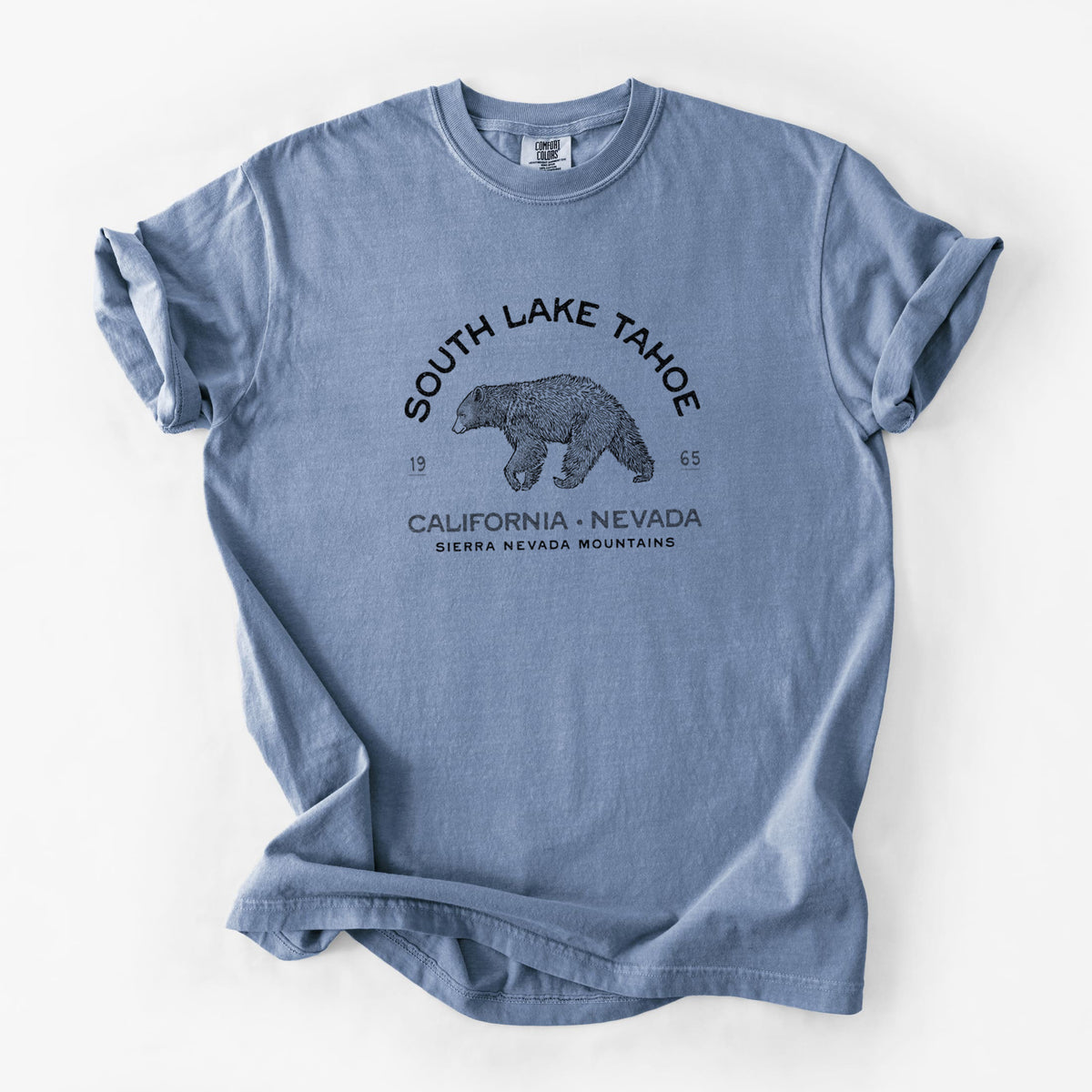 Blue jean Comfort Colors t-shirt laid flat, printed with a black ink bear with the words South Lake Tahoe, California - Nevada, Sierra Nevada Mountains.