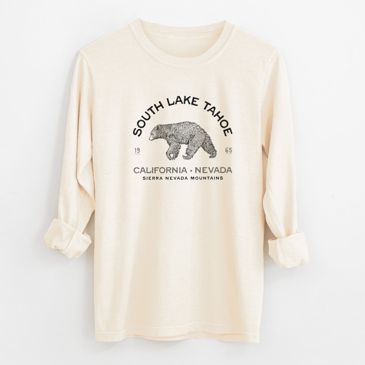 Ivory Comfort Colors long sleeve shirt laid flat with the cuffs rolled, printed with a black ink bear with the words South Lake Tahoe, California - Nevada, Sierra Nevada Mountains.