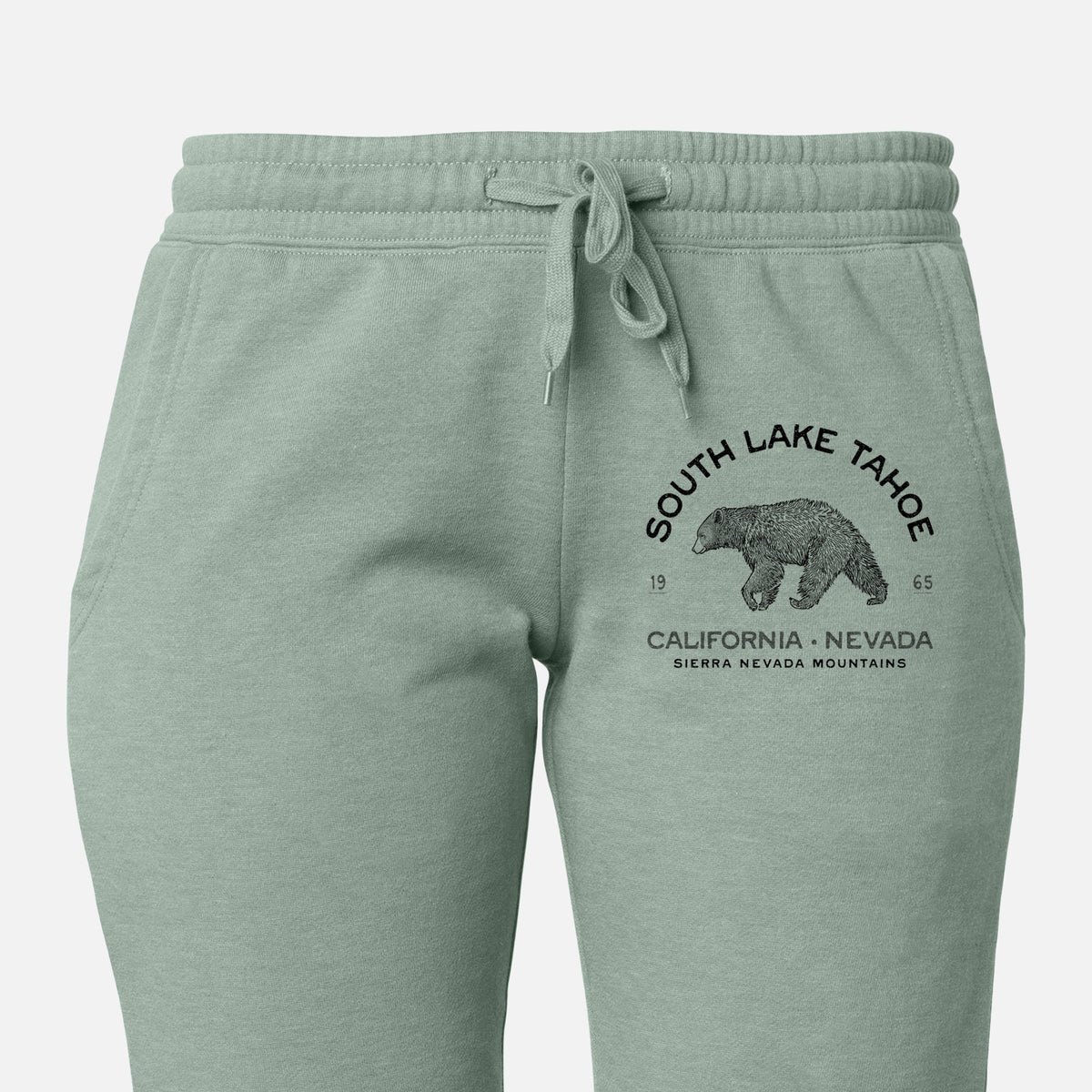 Front of sage green Cali Wave sweatpants, printed with a black ink bear with the words South Lake Tahoe, California - Nevada, Sierra Nevada Mountains on the leg.