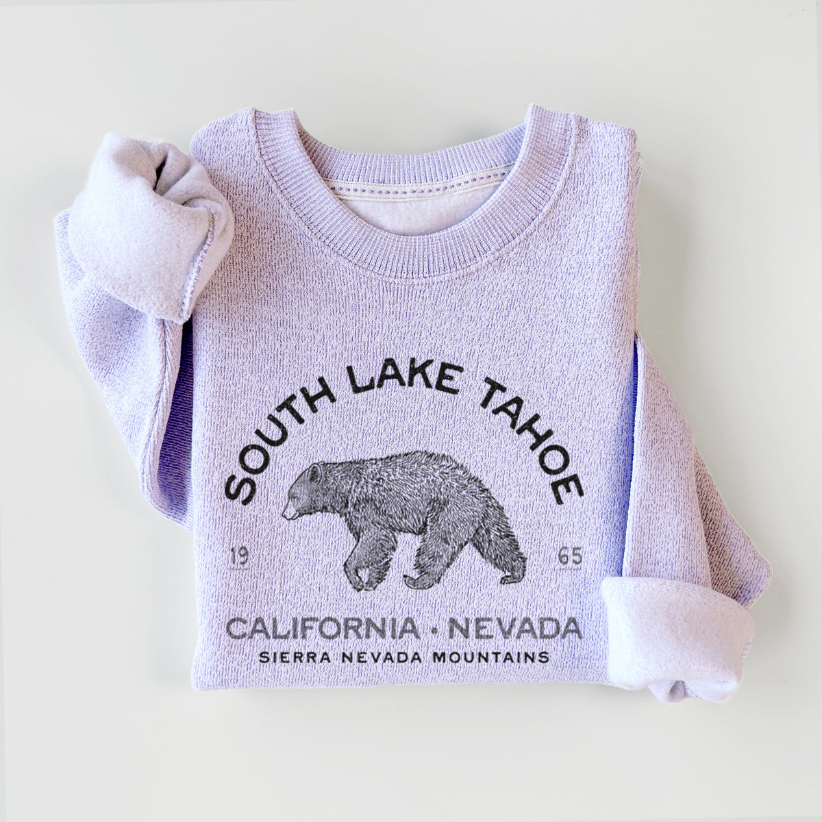 Ice purple knit sweatshirt printed with a black ink bear with the words South Lake Tahoe, California - Nevada, Sierra Nevada Mountains, styled flat.