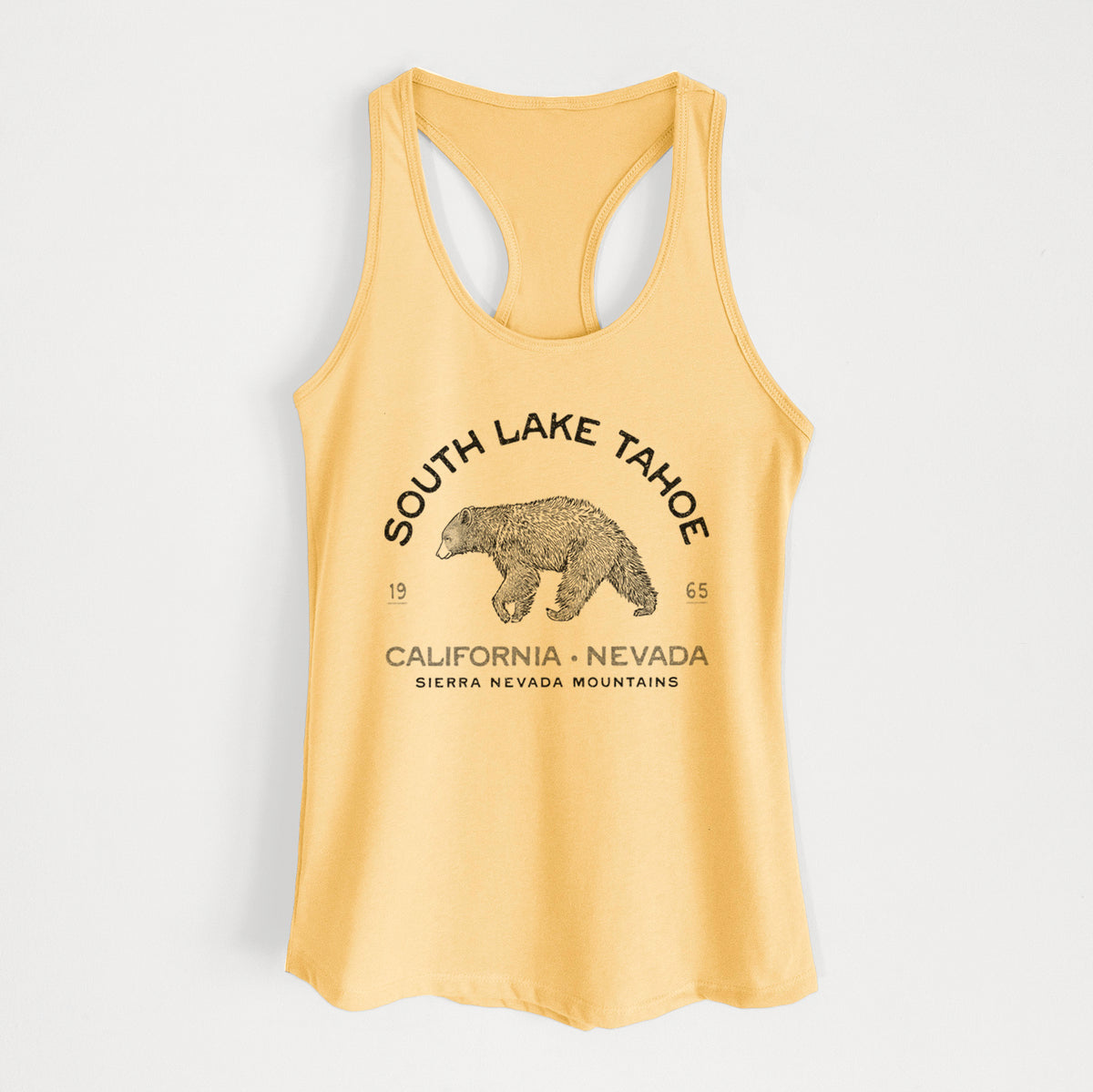 Banana cream women's racerback tank top laid flat, printed with a black ink bear with the words South Lake Tahoe, California - Nevada, Sierra Nevada Mountains.