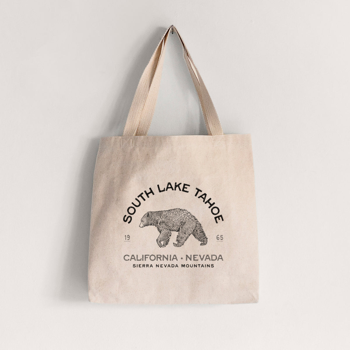 Natural canvas tote bag printed with a black ink bear with the words South Lake Tahoe, California - Nevada, Sierra Nevada Mountains.