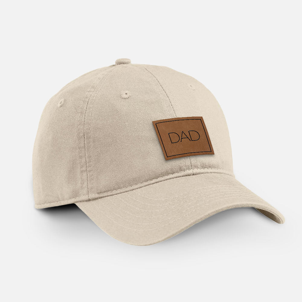 Stone cotton baseball hat with a brown leather patch engraved with the word DAD in a square on the front.