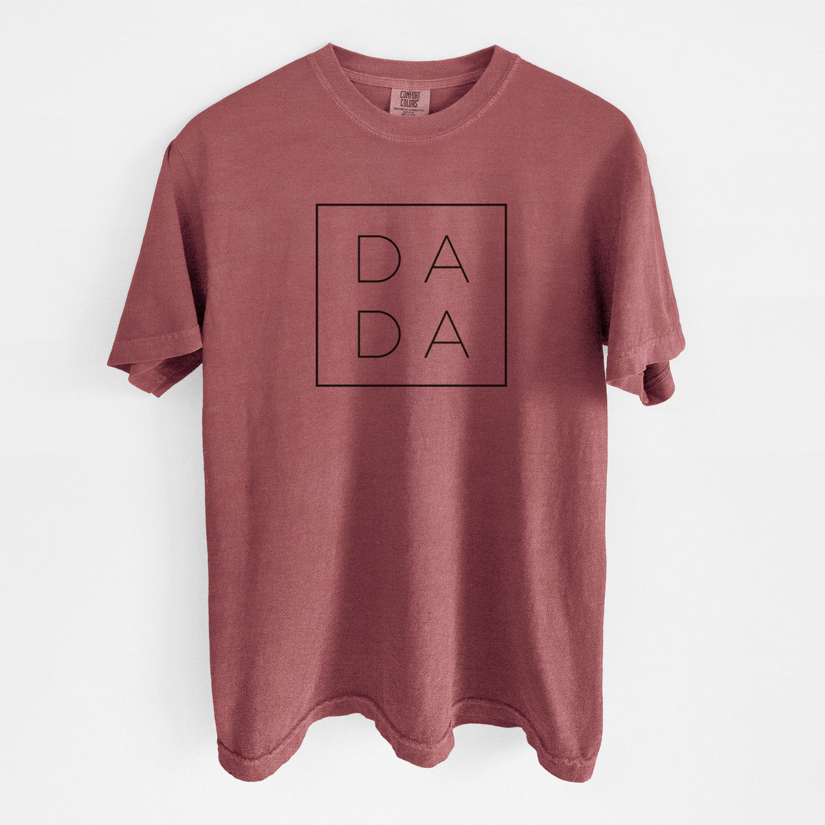 Brick red Comfort Colors t-shirt laid flat, printed with the word DADA in thin black letters stacked inside a square outline.