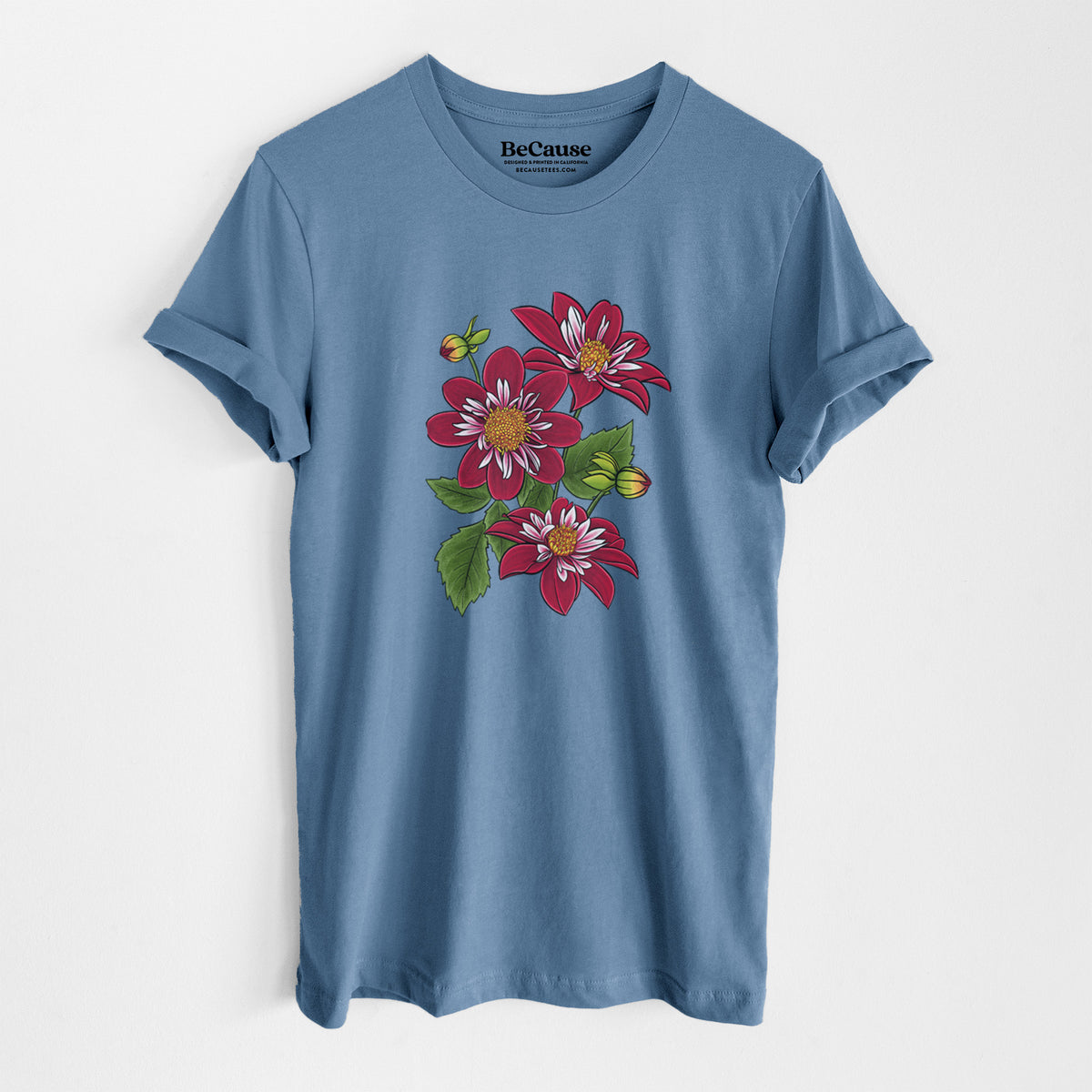 Steel blue lightweight cotton t-shirt laid flat, printed with a full-color illustration of deep red dahlia flowers with green leaves and a small bee.