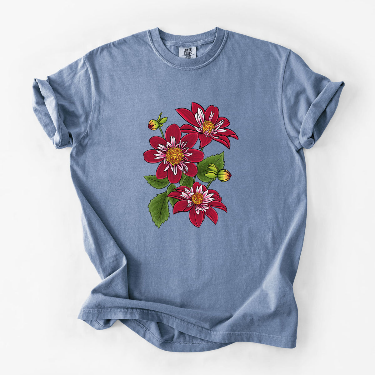 Blue jean Comfort Colors t-shirt laid flat, printed with a full-color illustration of deep red dahlia flowers with green leaves and a small bee.