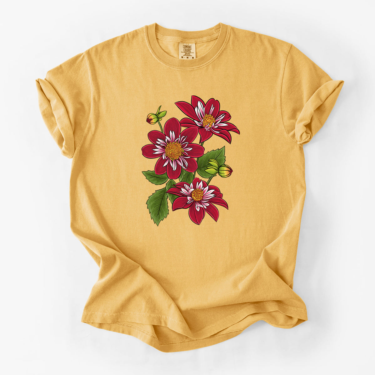 Golden wheat yellow Comfort Colors t-shirt laid flat, printed with a full-color illustration of deep red dahlia flowers with green leaves and a small bee.