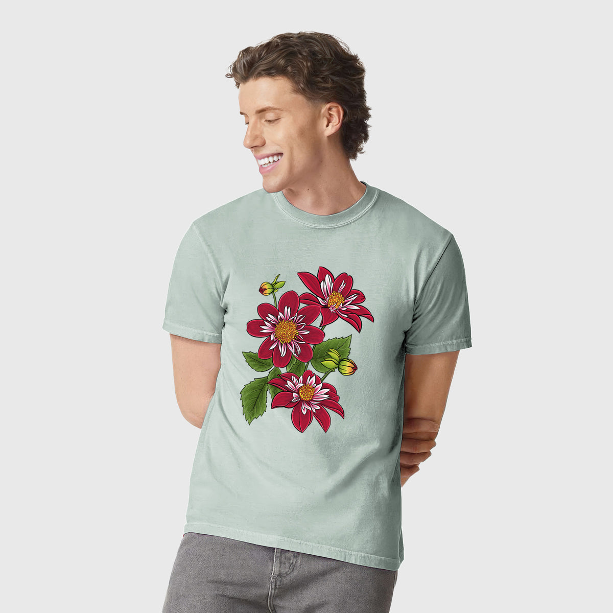 Man wearing a Comfort Colors t-shirt printed with a full-color illustration of deep red dahlia flowers with green leaves and a small bee.
