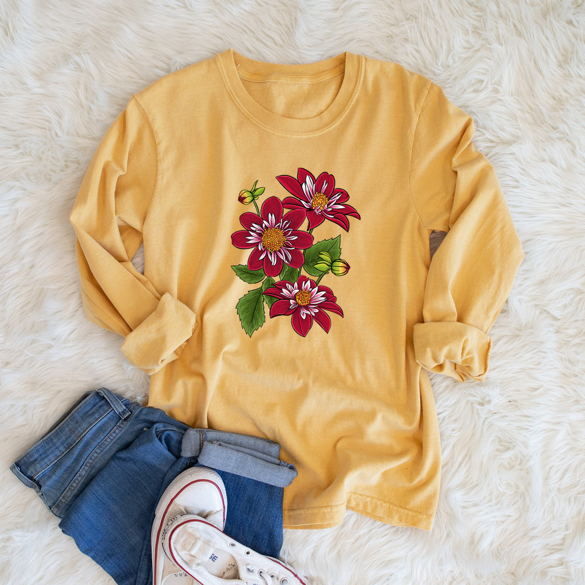 Golden wheat yellow Comfort Colors long sleeve shirt printed with a full-color illustration of deep red dahlia flowers with green leaves and a small bee, shown in a lifestyle photo.