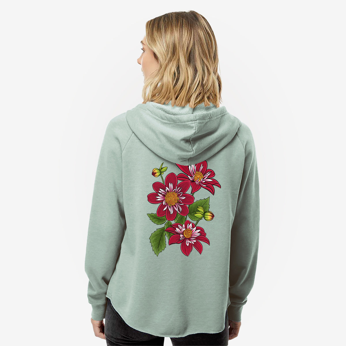 Woman wearing a sage green women's Cali Wave zip-up sweatshirt printed with a full-color illustration of deep red dahlia flowers with green leaves and a small bee, seen from behind.