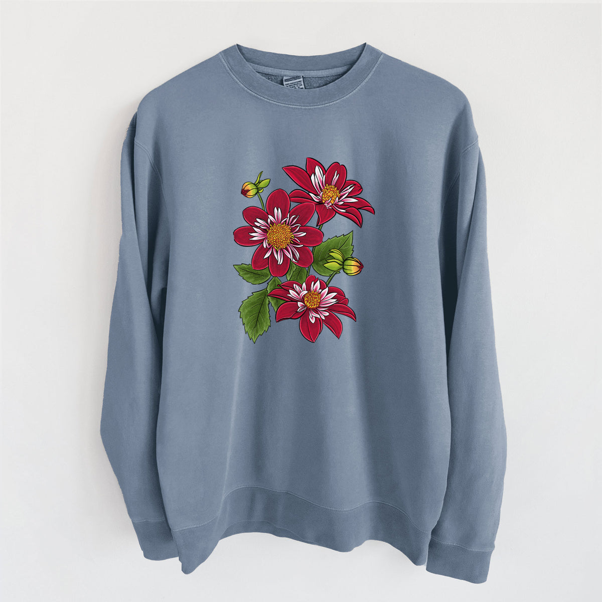 Slate blue pigment dyed crewneck sweatshirt laid flat, printed with a full-color illustration of deep red dahlia flowers with green leaves and a small bee.