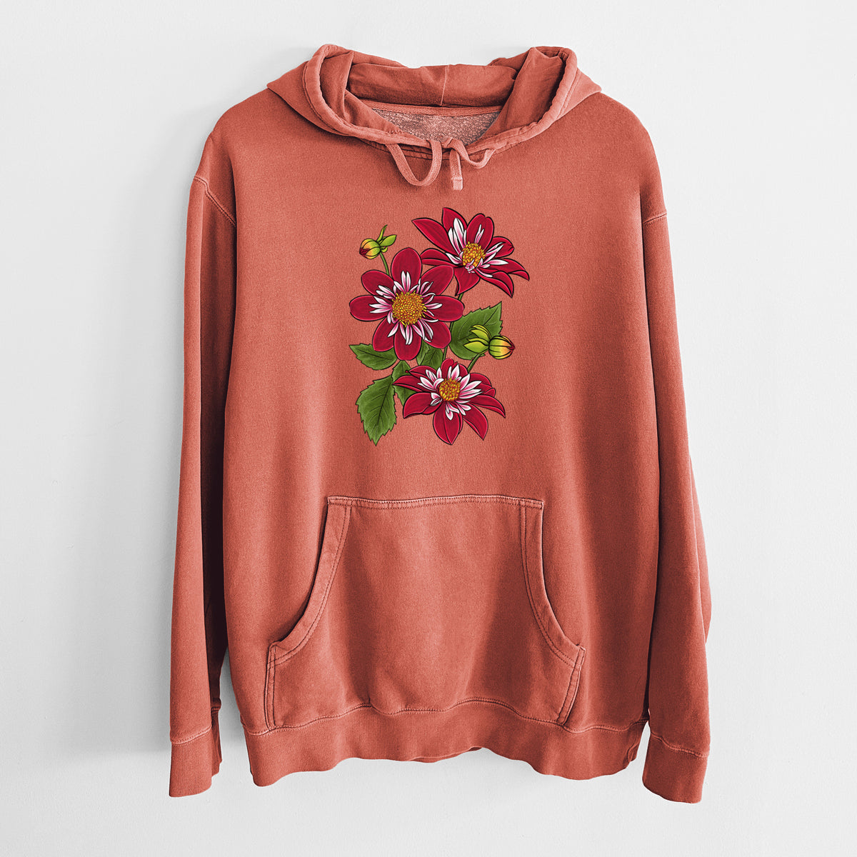 Amber orange pigment dyed hoodie laid flat, printed with a full-color illustration of deep red dahlia flowers with green leaves and a small bee.